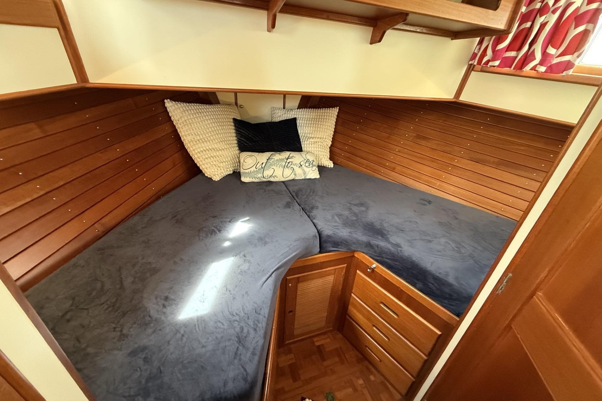 Cozy cabin interior of 1999 Grand Banks 42 Classic yacht with wooden paneling and bedding.