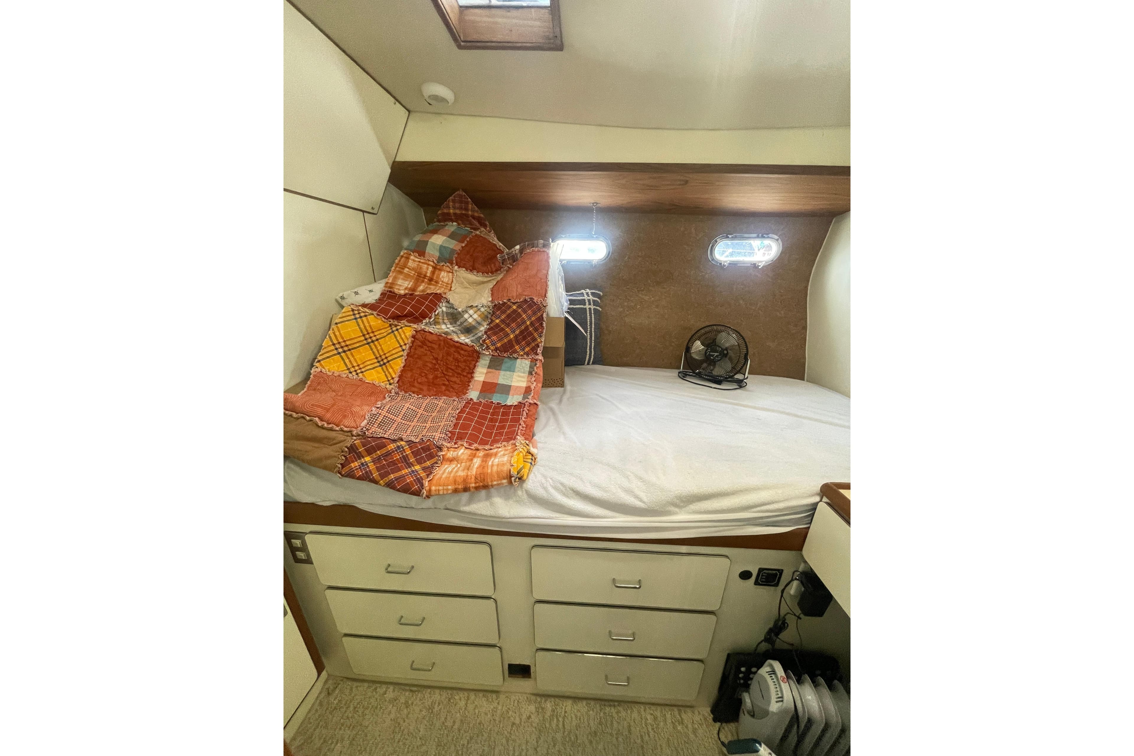 Cozy cabin interior of 1986 Hi-Star 40 Flybridge with patchwork quilt and storage drawers.
