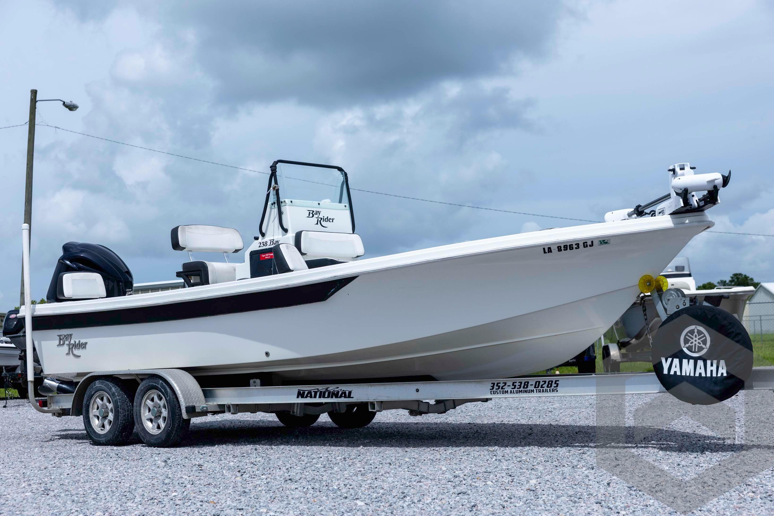 2018 Bay Rider 238 Bay boat on trailer with Yamaha motor, parked on gravel.