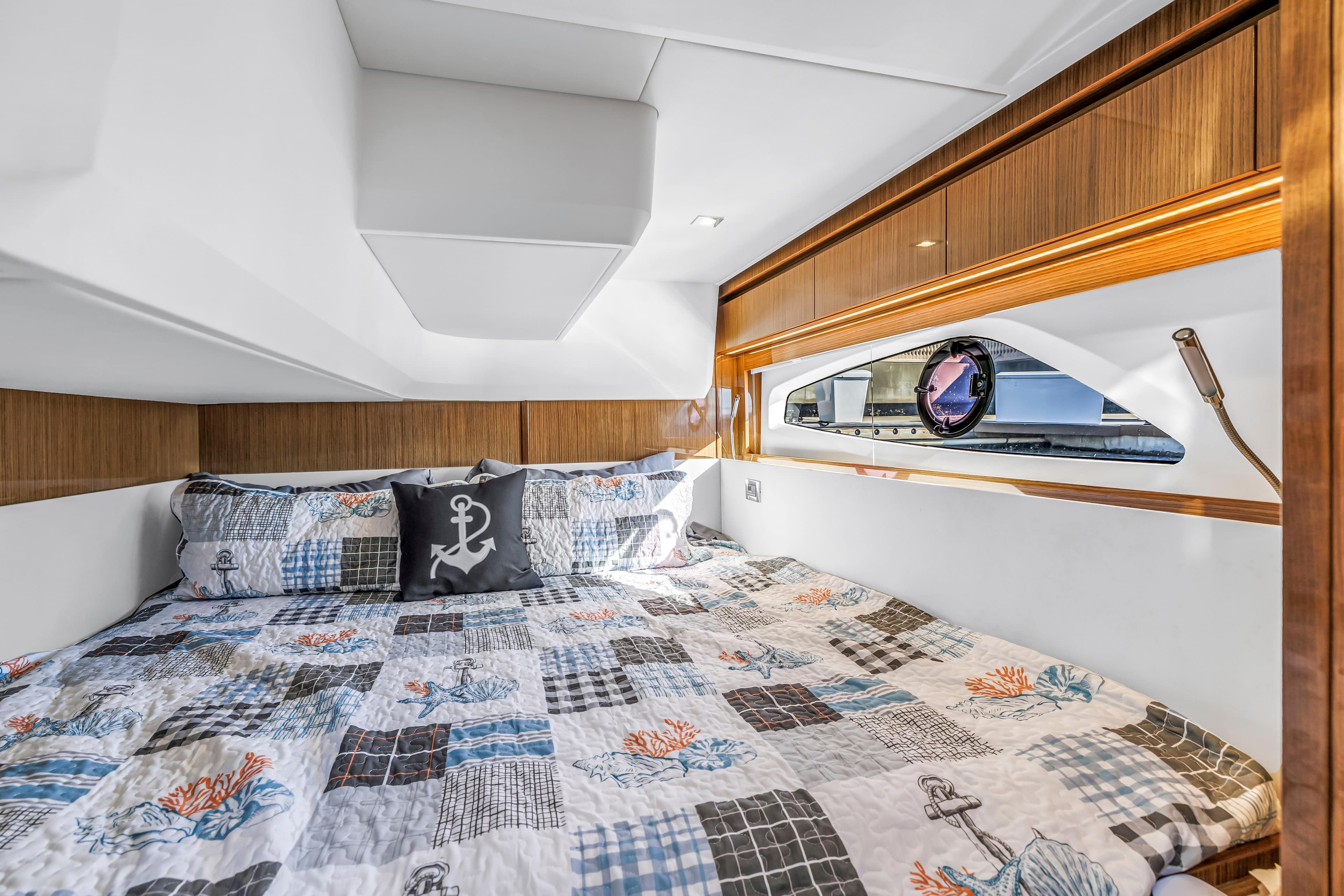 Luxurious cabin interior of 2020 Sealine C390 yacht with nautical-themed bedding.