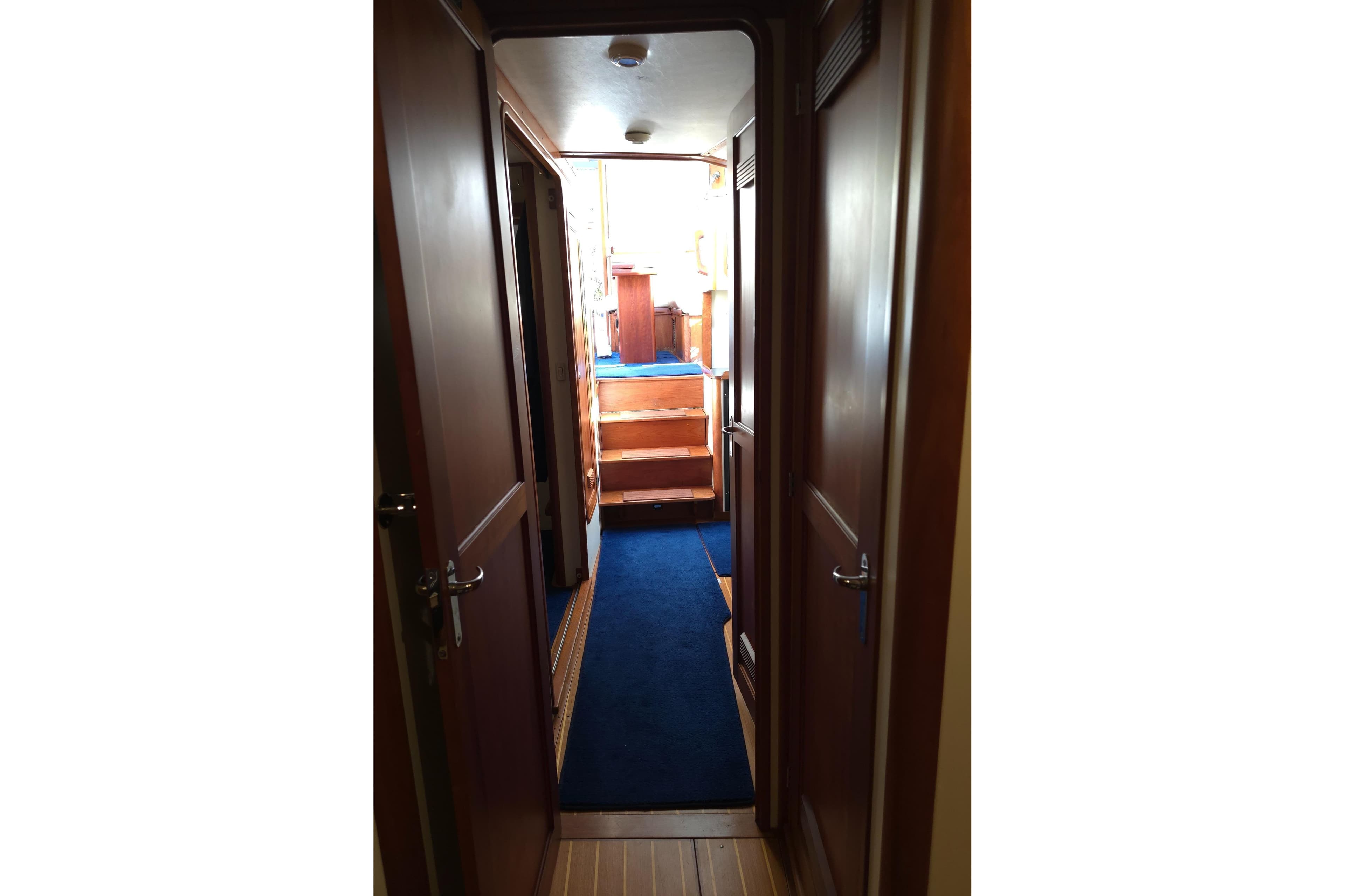 Interior hallway of 2004 Legacy Yachts Sedan Flybridge with blue carpet and wooden doors.