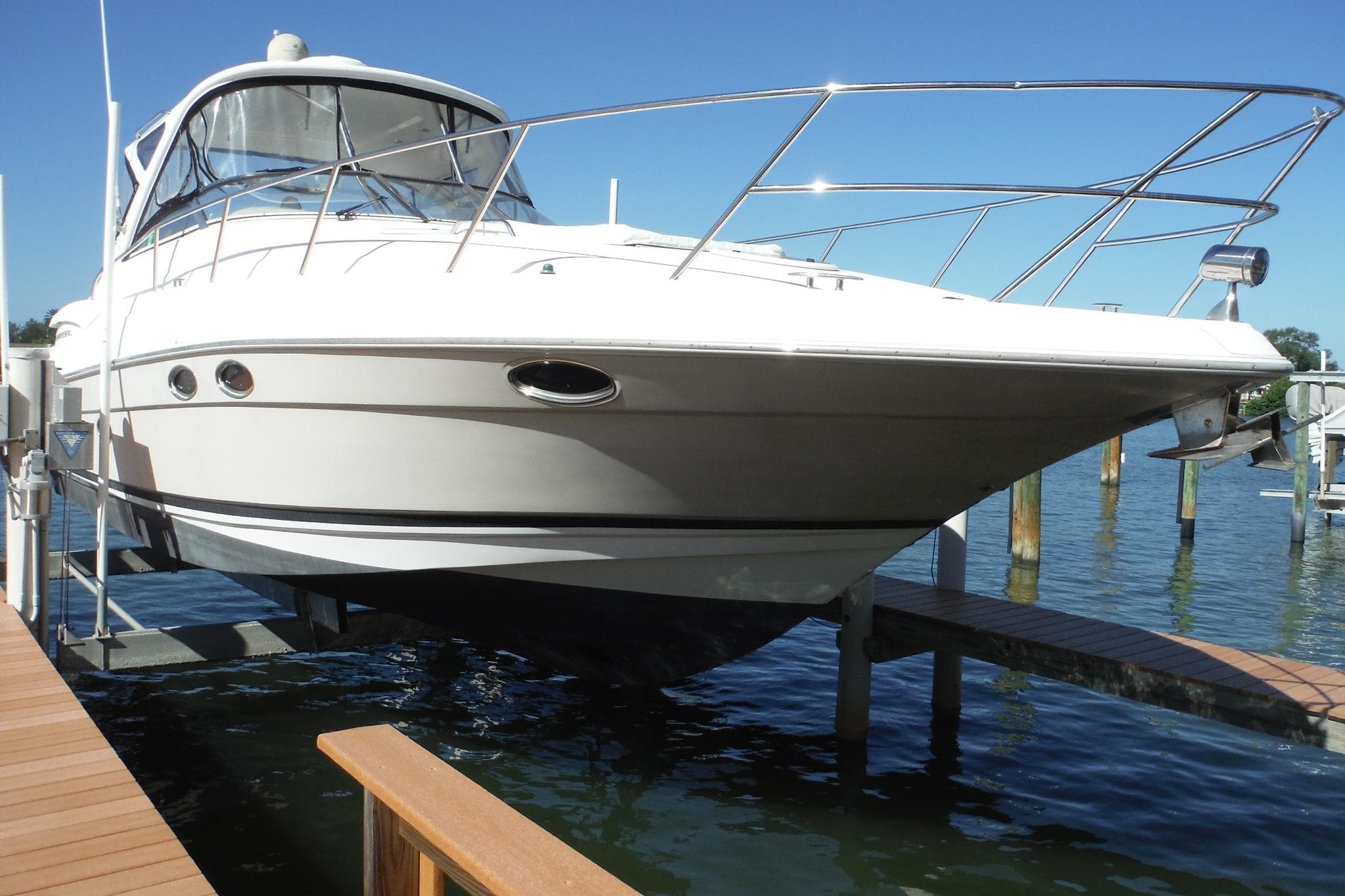 2008 Regal Commodore 3760 IO boat docked on a lift, clear blue sky background.