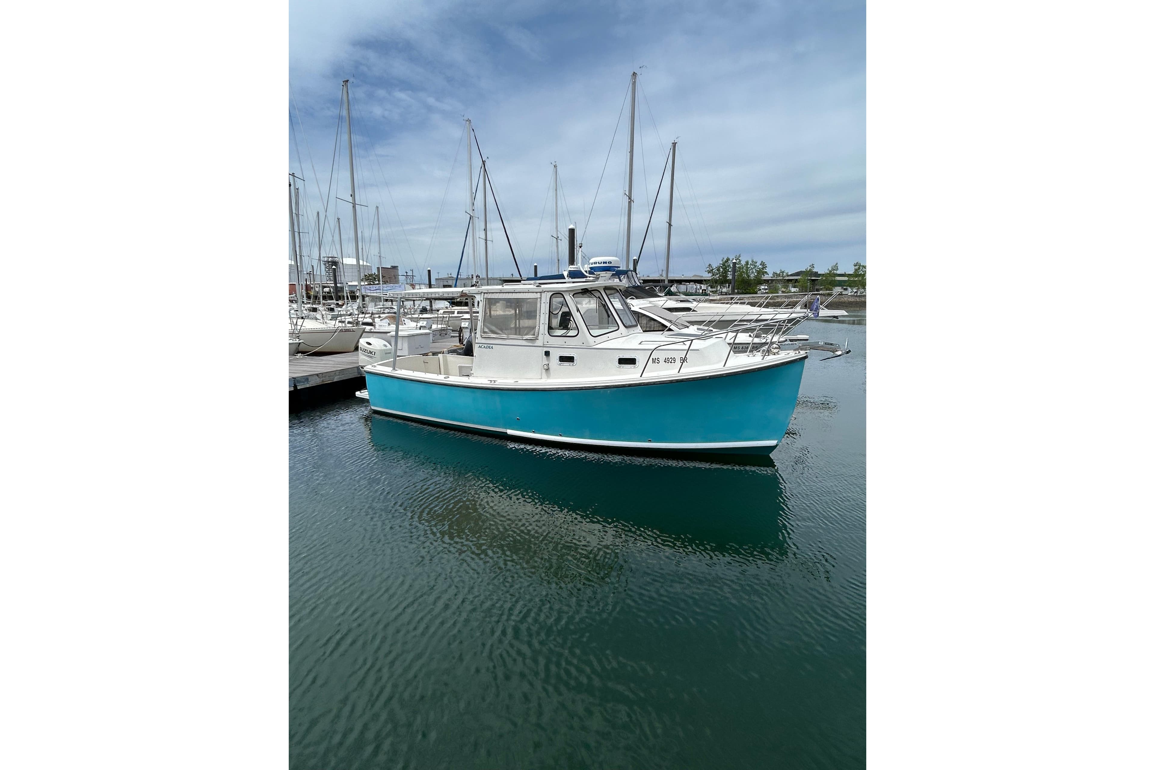 2018 Atlas Boat Works Acadia docked in a marina, surrounded by sailboats.