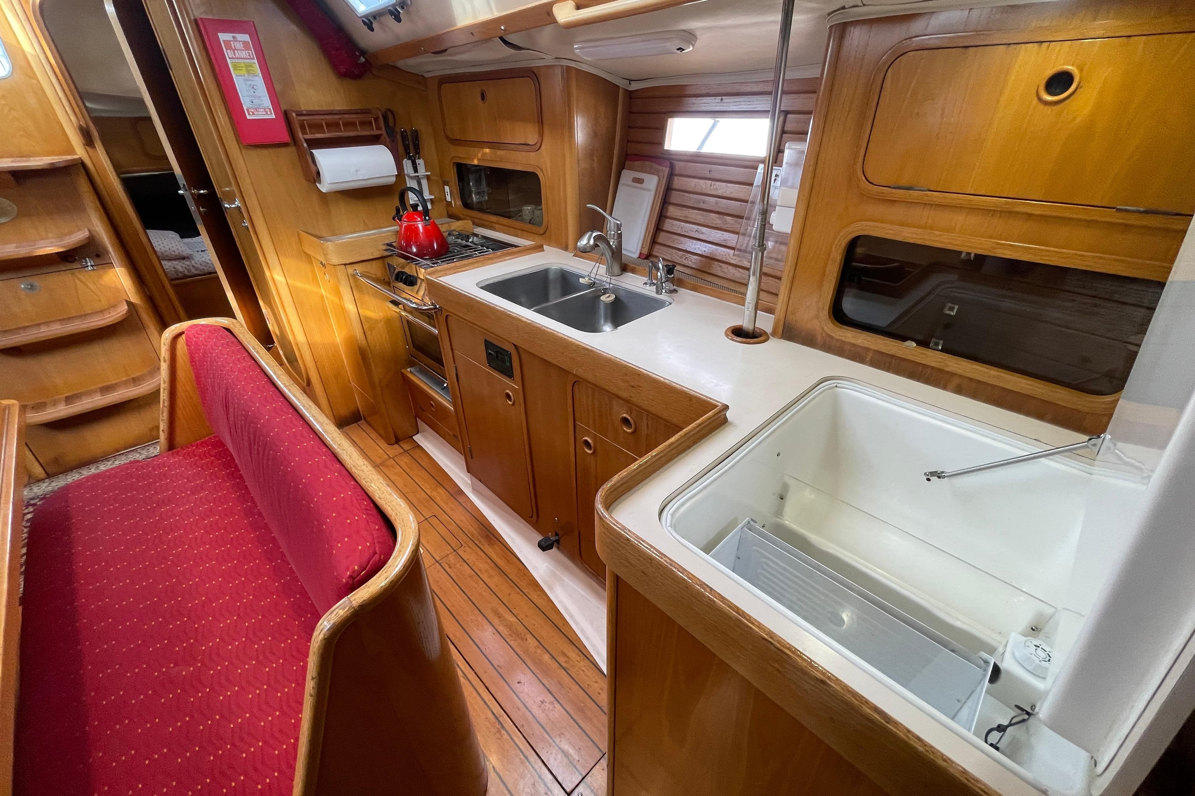 Interior of 1990 Beneteau Oceanis 390 yacht, featuring a cozy kitchen and seating area.