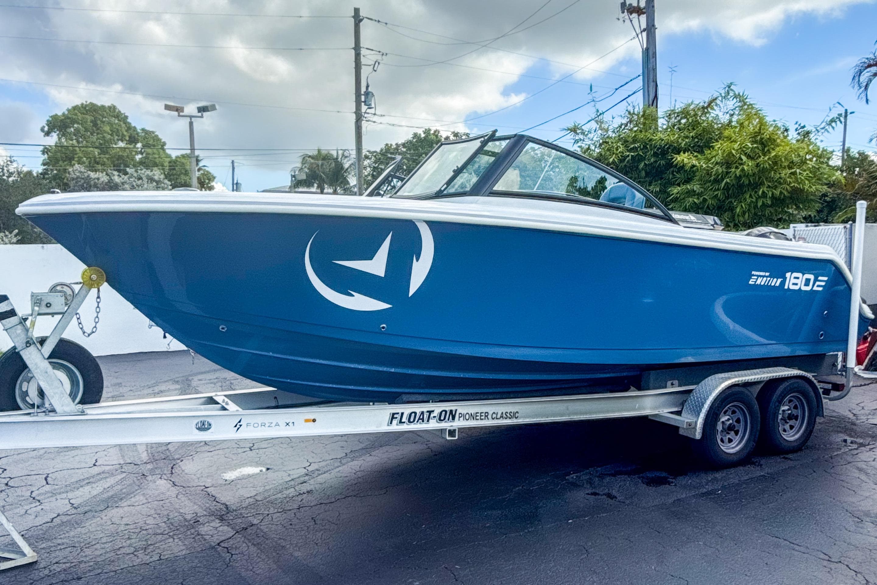 2024 Aquasport AS DC 22 boat on trailer, blue hull, parked outdoors.