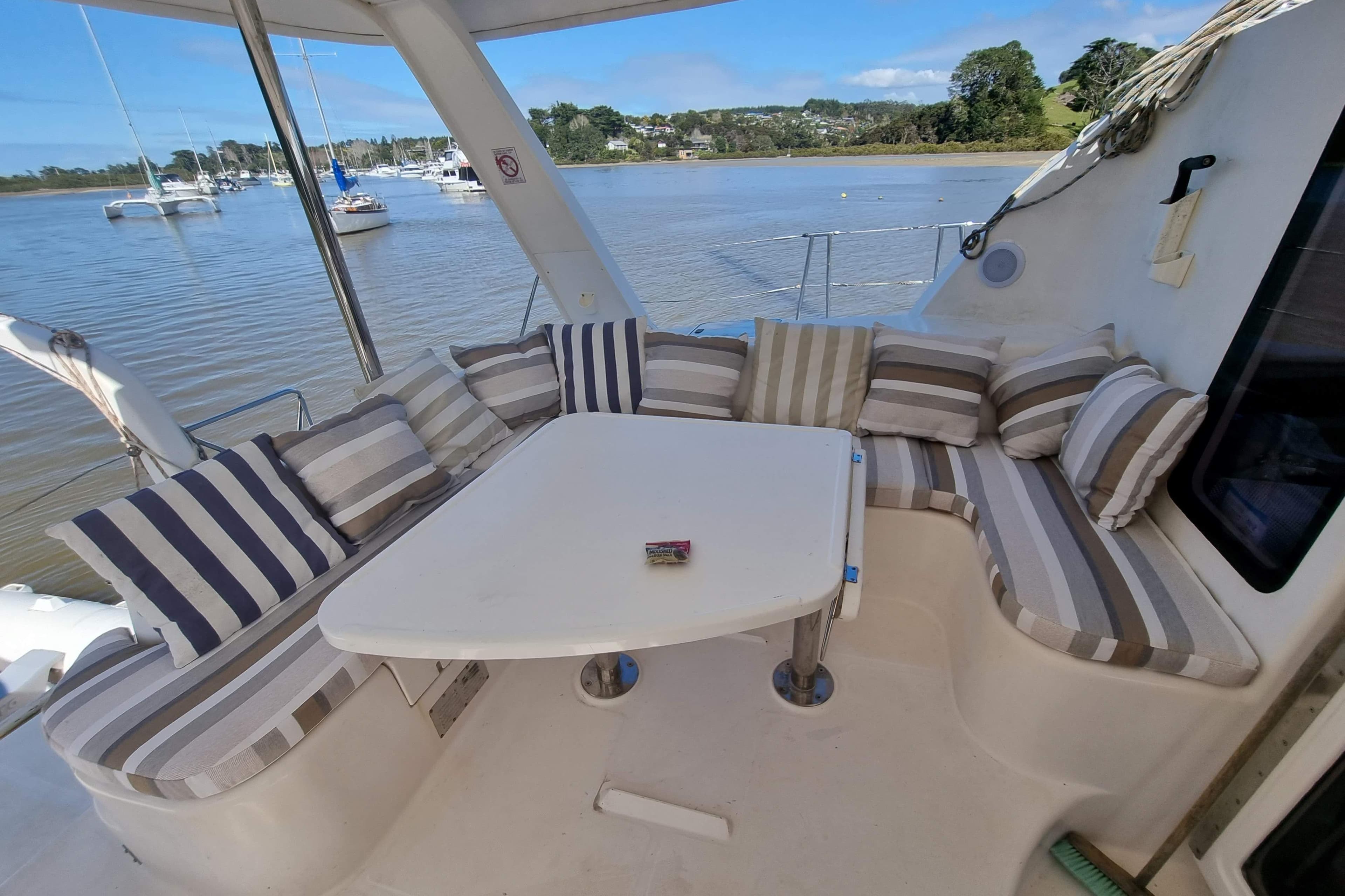 Cozy seating area on 2007 Leopard 43 yacht with striped cushions, overlooking a serene marina.