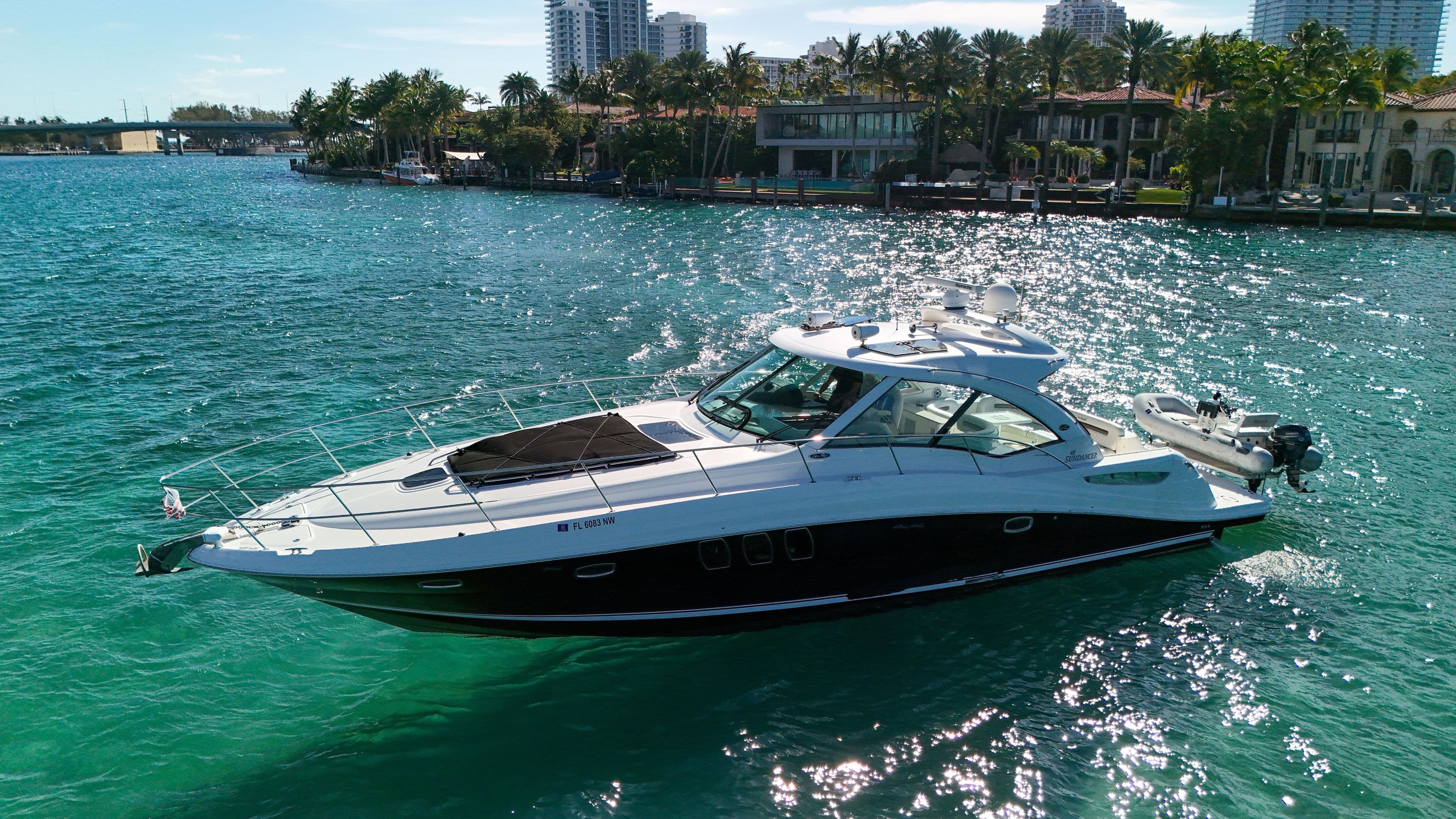 2008 Sea Ray 48 Sundancer yacht cruising on clear blue water near a tropical shoreline.