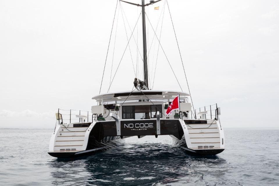 2016 HH Catamarans HH66 sailing catamaran on open water, rear view with flag.