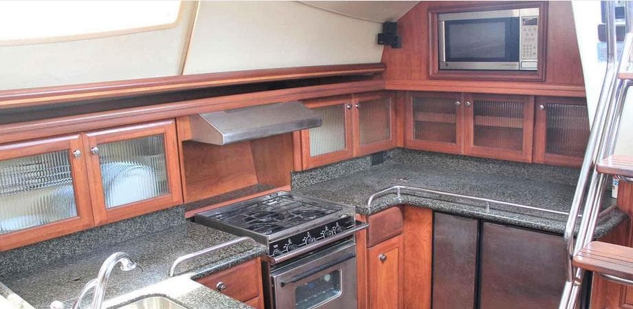 Modern kitchen in 2010 Hunter 50 Center Cockpit yacht with wood cabinets and granite countertops.