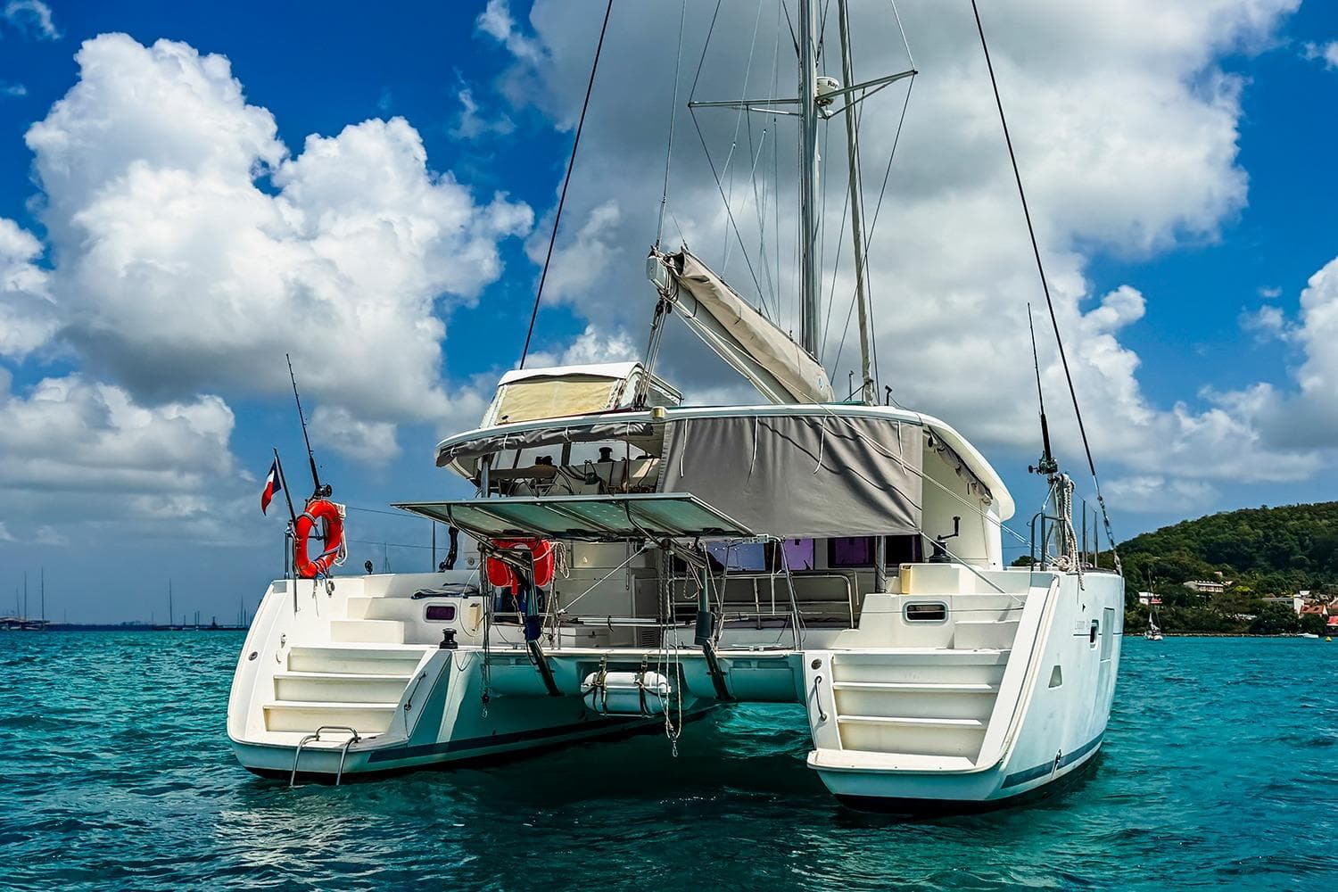 Lagoon 400 catamaran from 2010 on turquoise water under a blue sky with clouds.