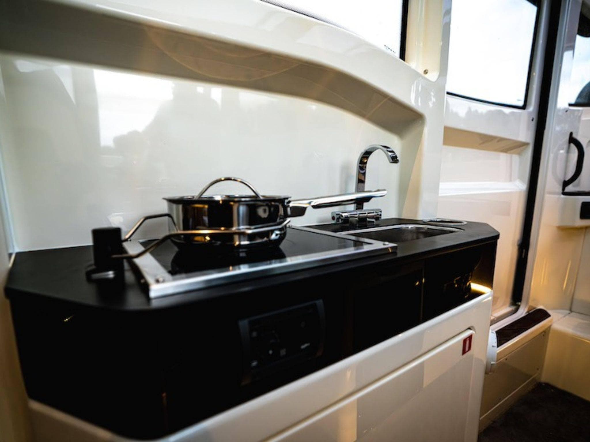 Compact kitchen area in a 2025 Navan C30, featuring a stove and sink.