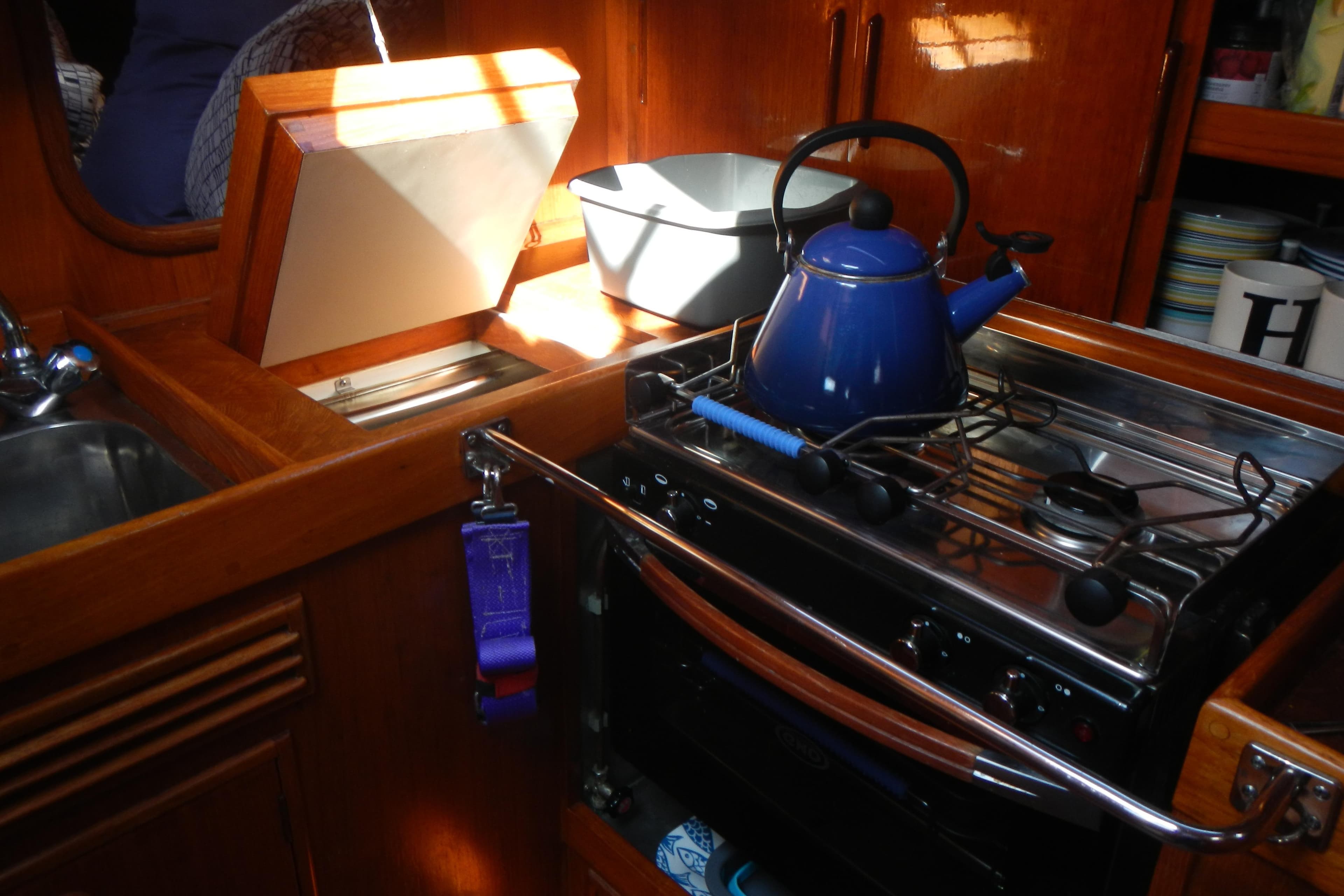 Cozy galley kitchen in 1980 Nautor Swan 411 yacht with blue kettle on stove.