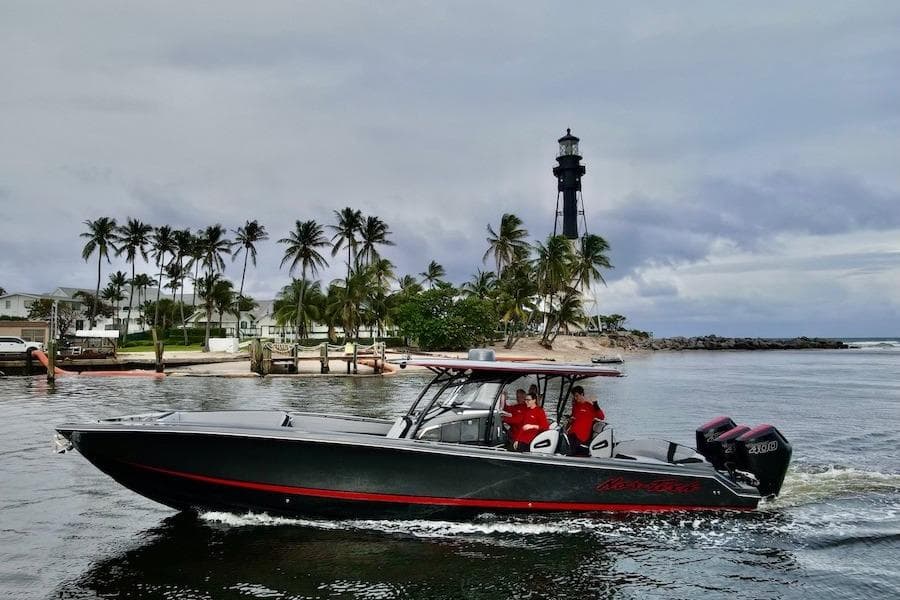 2025 Nor-Tech 390 Sport Center Console boat cruising near a lighthouse and palm trees.