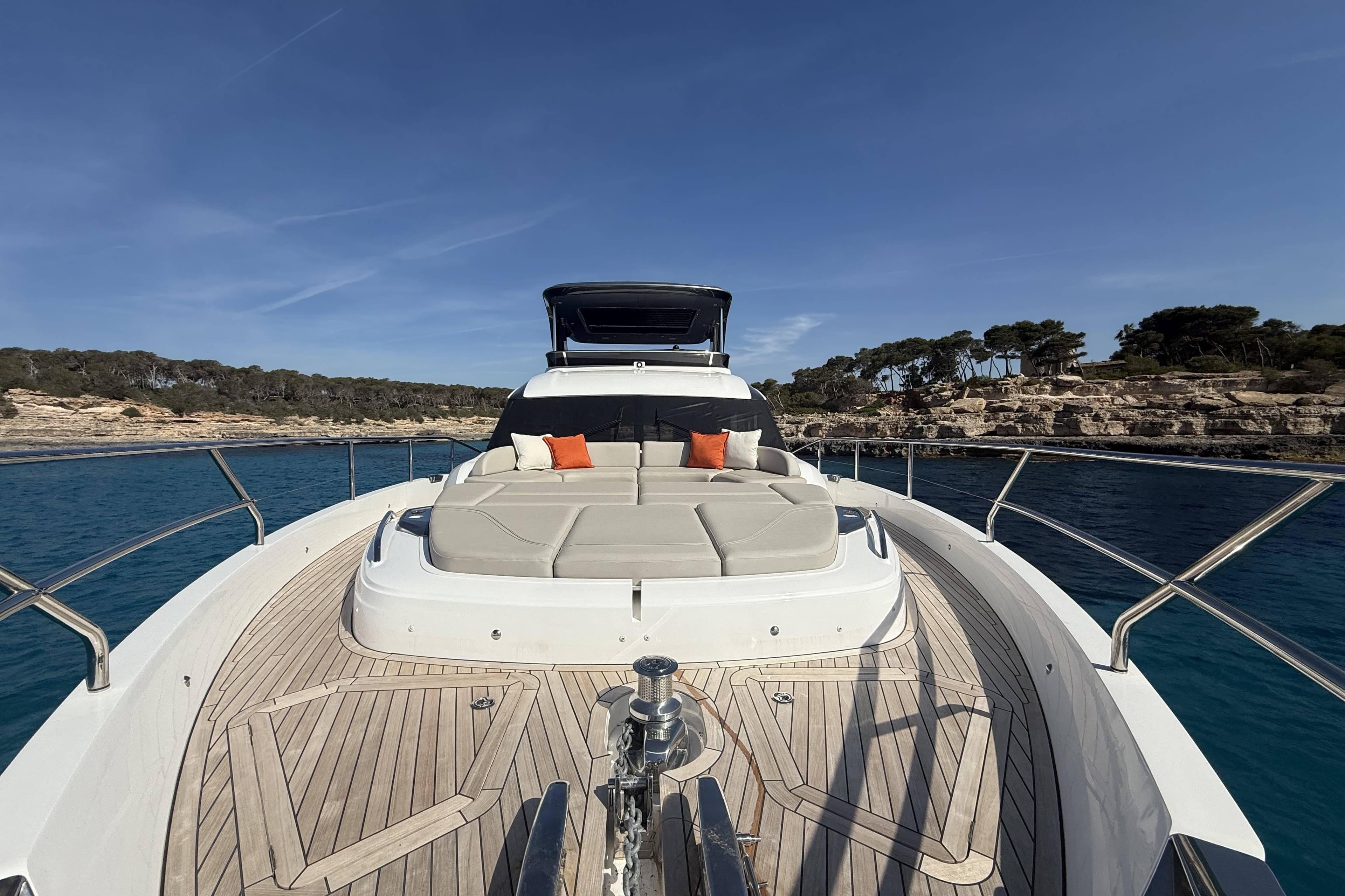 Luxurious 2025 Princess Y72 yacht deck with sun loungers, cruising near rocky coastline.