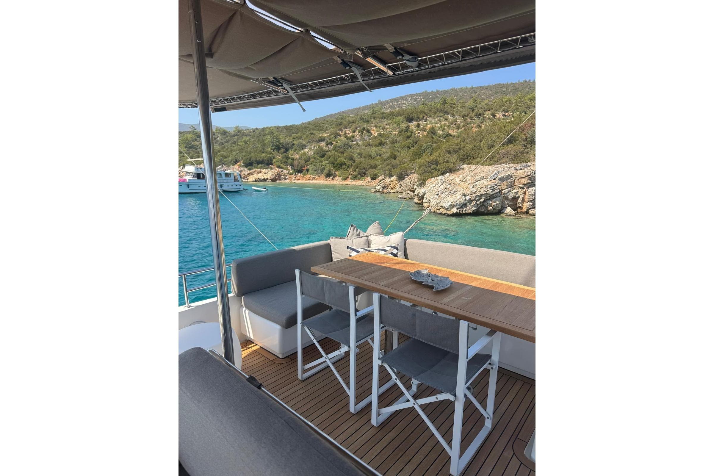 Lagoon 560 S2 yacht deck with seating, overlooking turquoise waters and rocky shoreline, 2015 model.