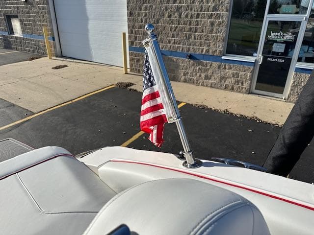 2025 Regal LS9 Surf boat with American flag on deck, parked near a building.