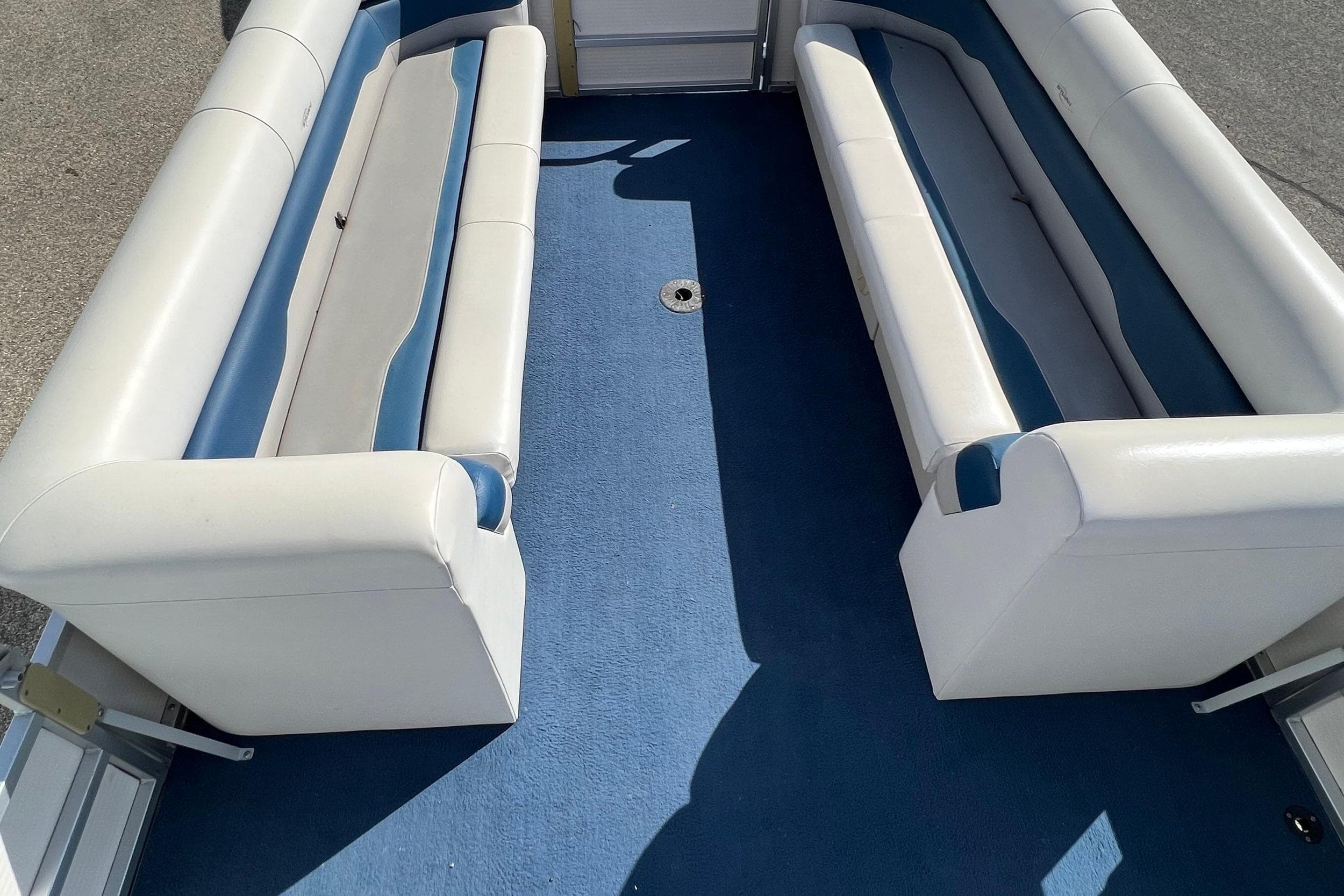 2003 Sylvan 824 Mirage Cruise interior with blue carpet and white seating.