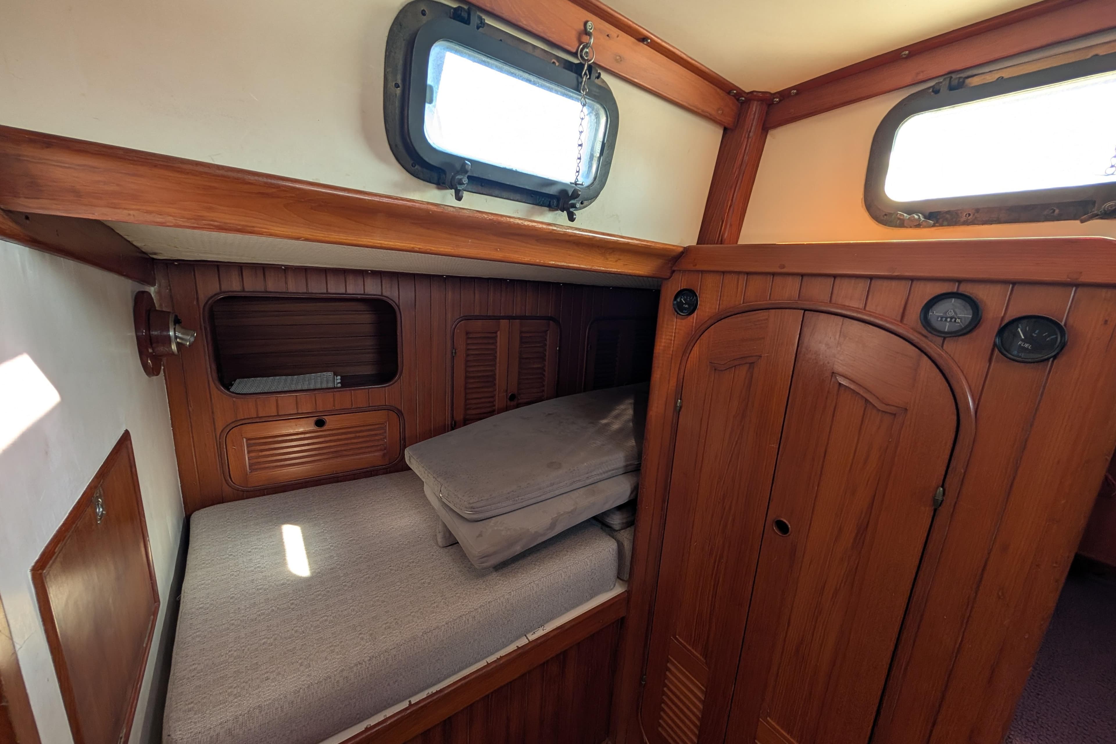 Cozy cabin interior of 1981 Mason 43 sailboat with wooden paneling and portholes.