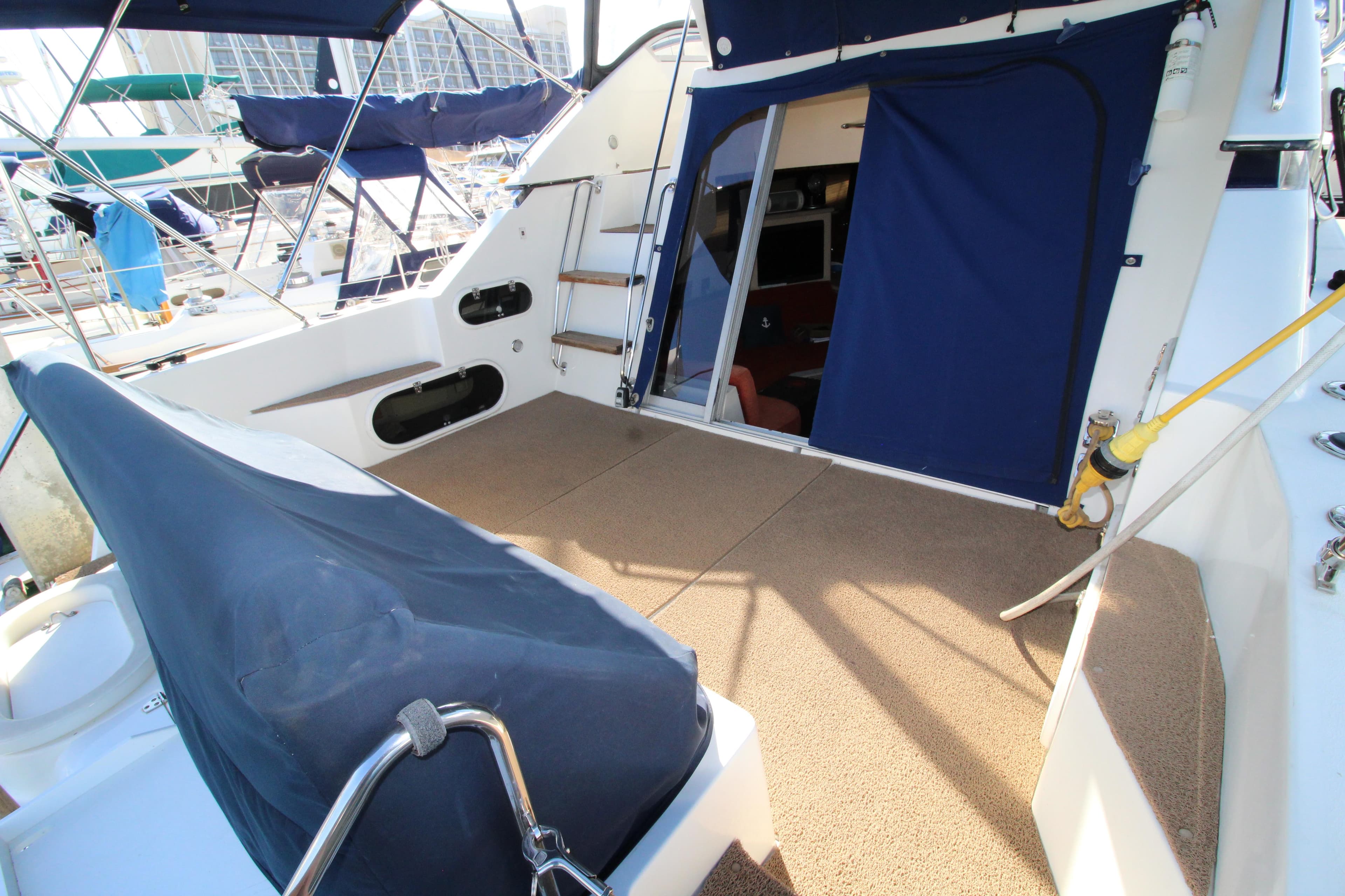 1990 Carver 3467 Santego yacht deck with blue canvas cover and open cabin door.