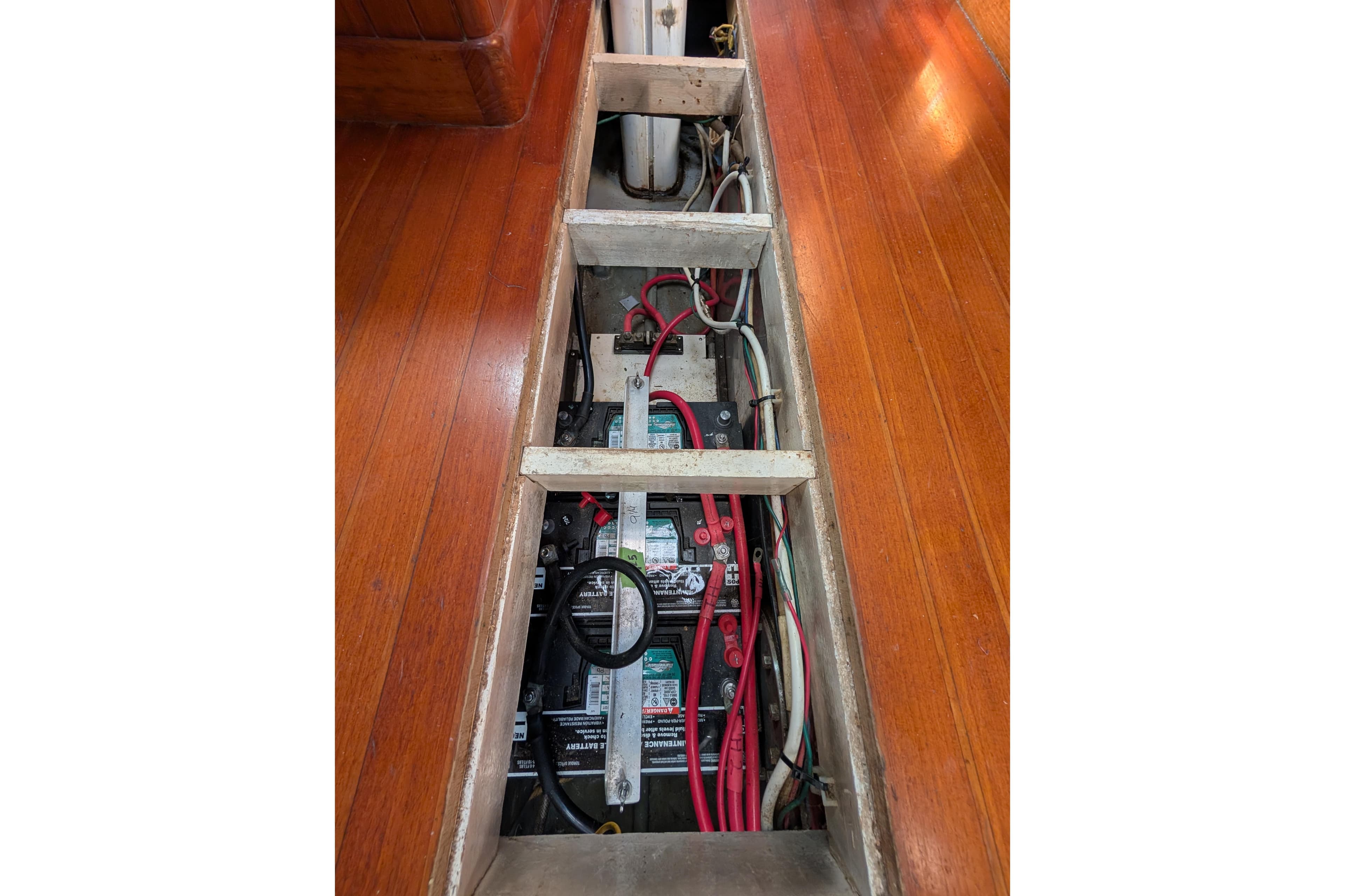 Battery compartment of a 1981 Mason 43 boat with visible wiring and wooden flooring.