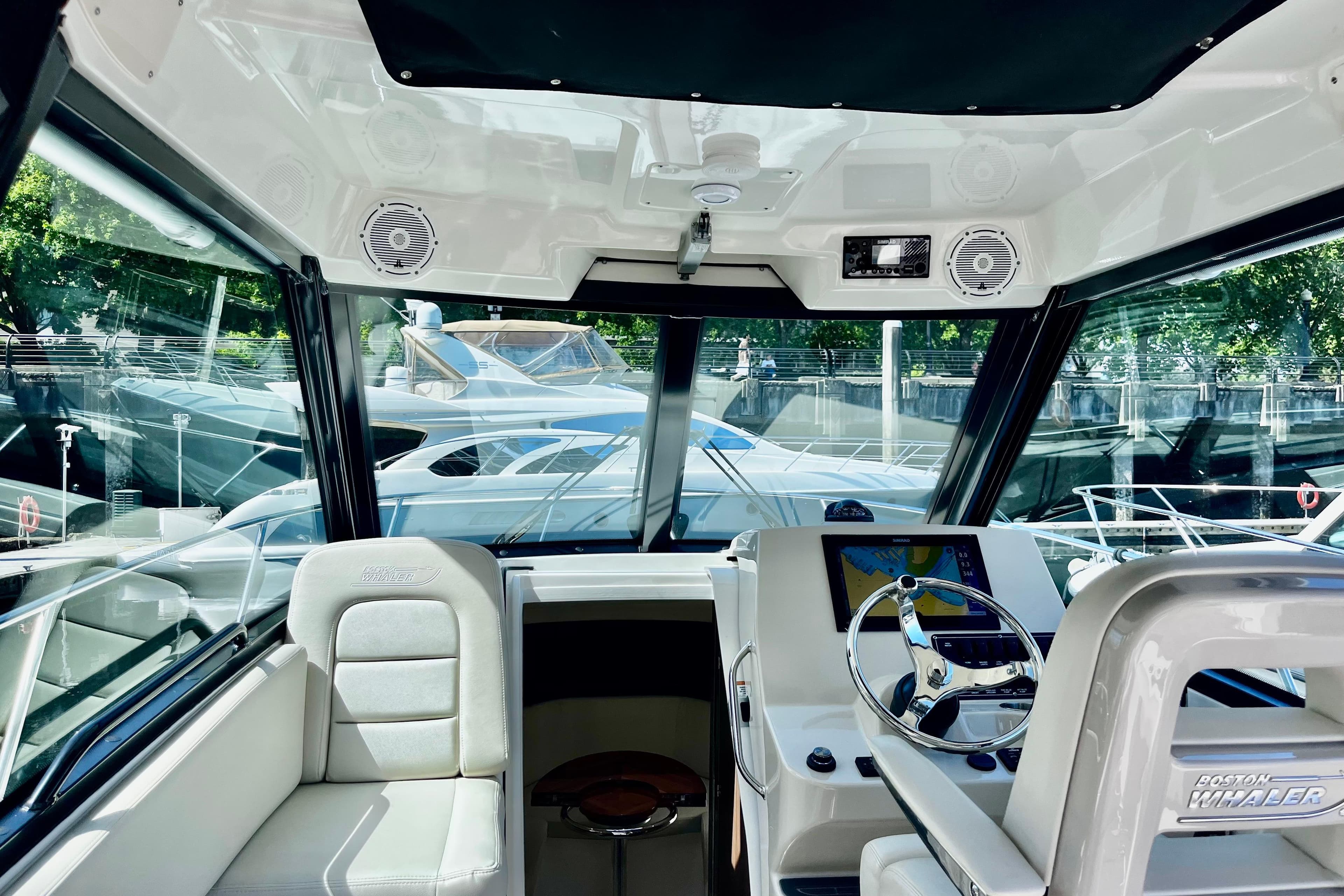 Interior view of 2023 Boston Whaler 285 Conquest boat cockpit with steering wheel and navigation system.