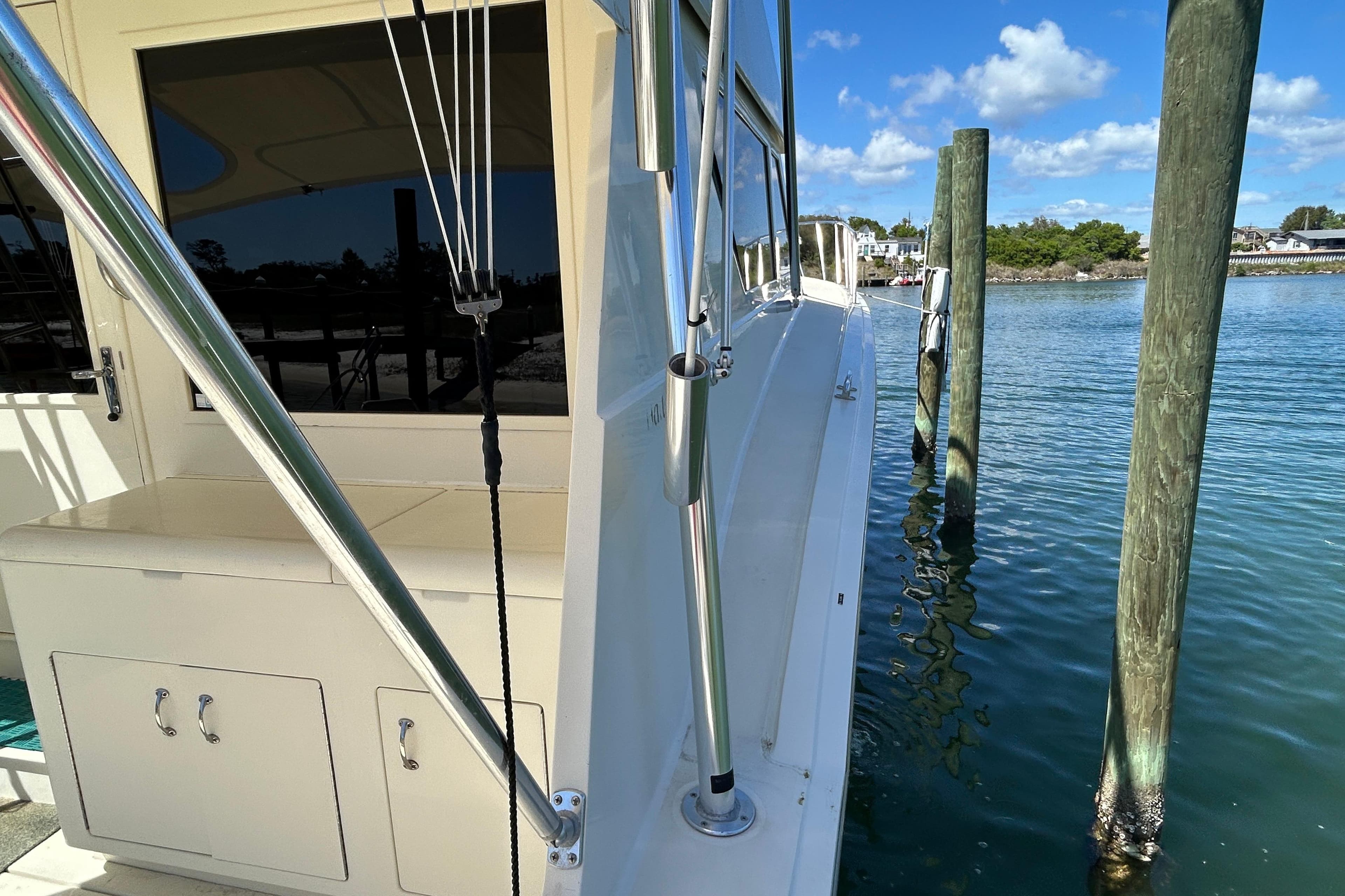 1989 Hatteras 45 Convertible yacht docked by wooden posts on a sunny day.