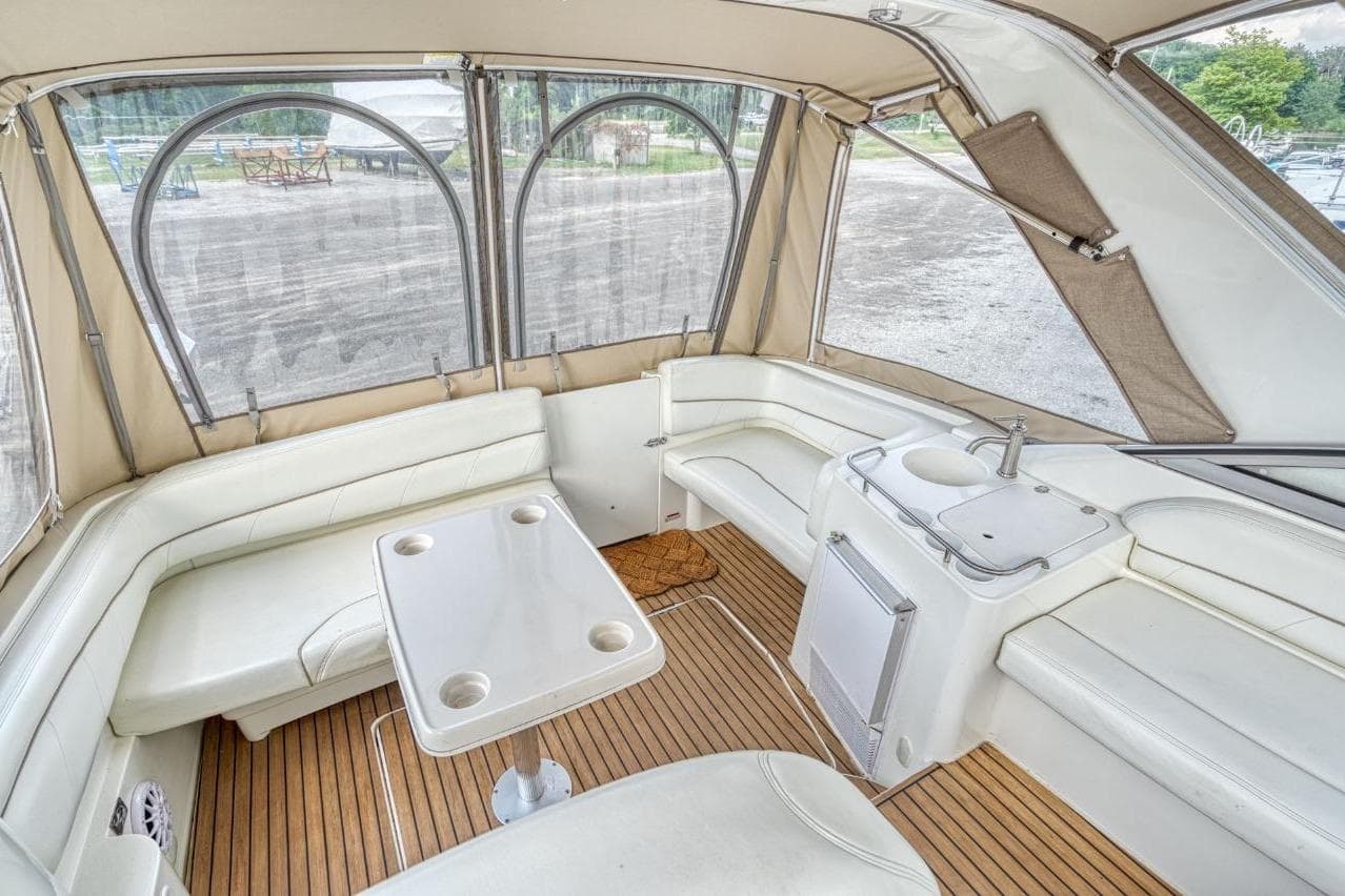 2002 Larson Cabrio 330 boat interior with white seating, table, and kitchenette.