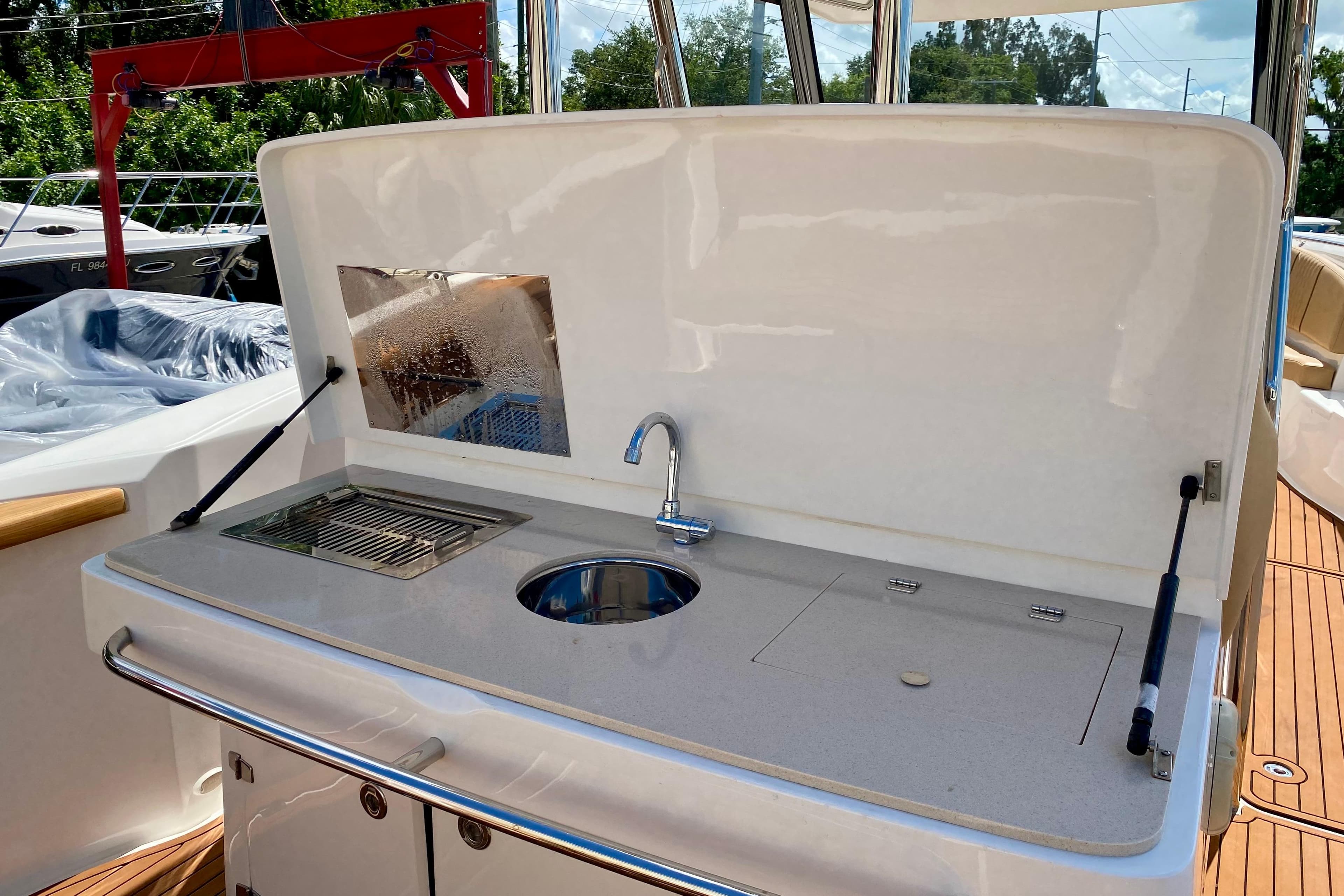 Outdoor kitchen on 2023 Fishing Raptor 390 Solarium boat with sink and grill.