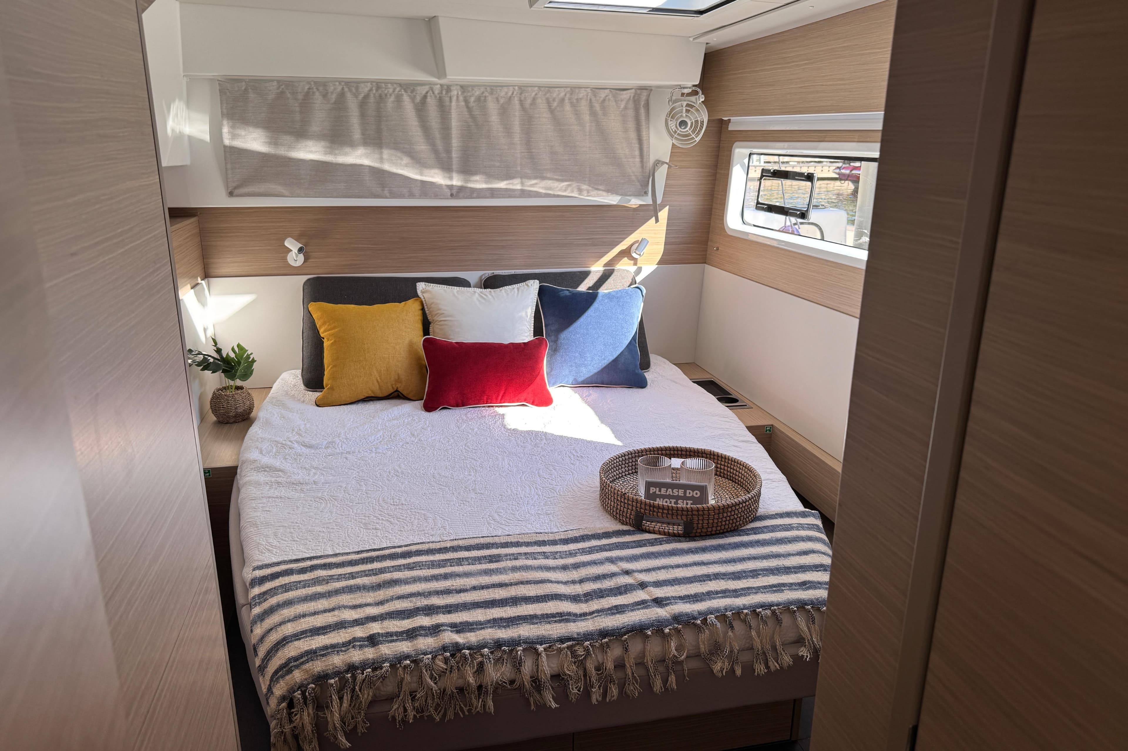 Luxurious bedroom interior of 2026 Lagoon 43 yacht with cozy bedding and natural light.