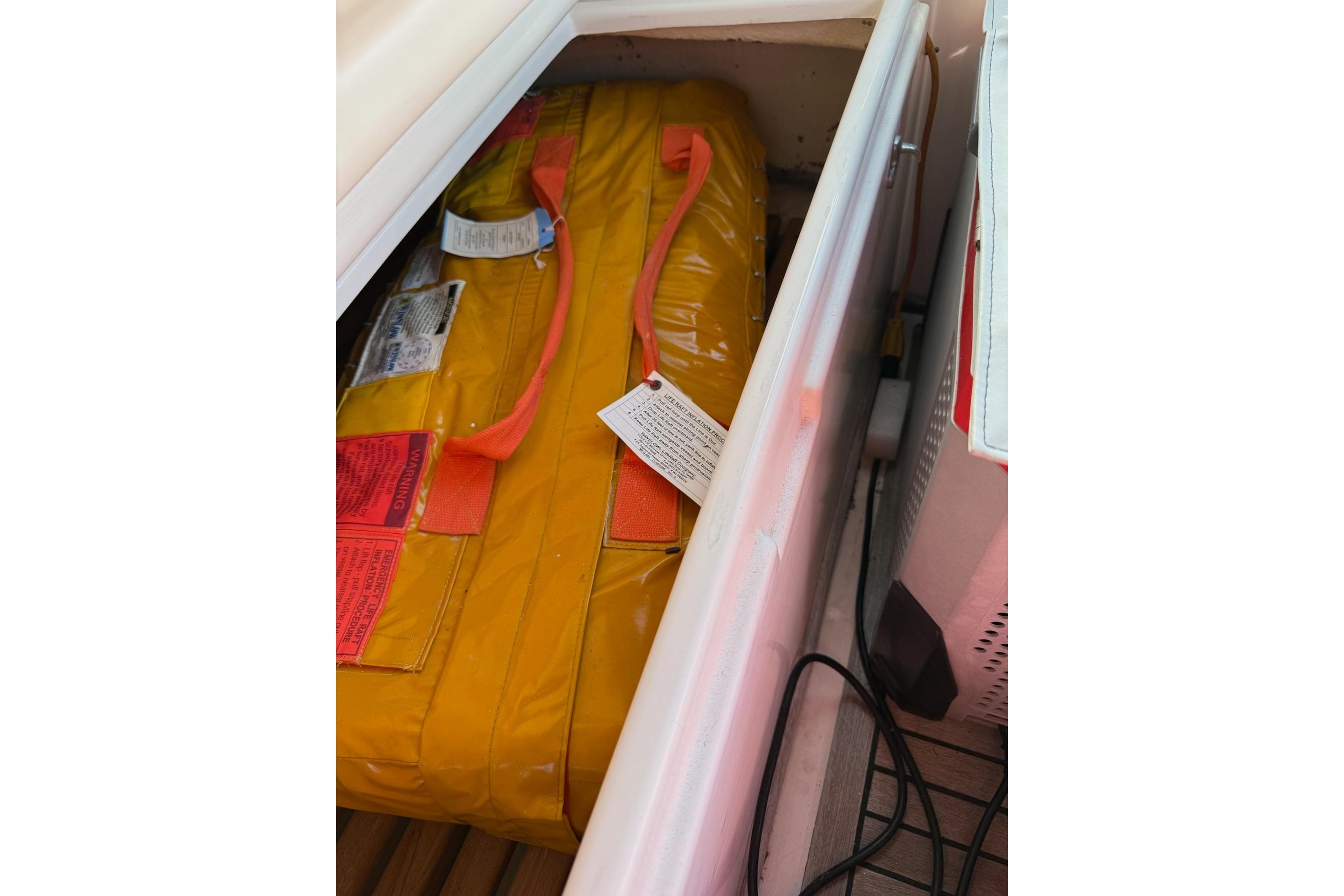 Yellow safety equipment stored in a compartment on a 2002 Grand Banks 42 Classic boat.