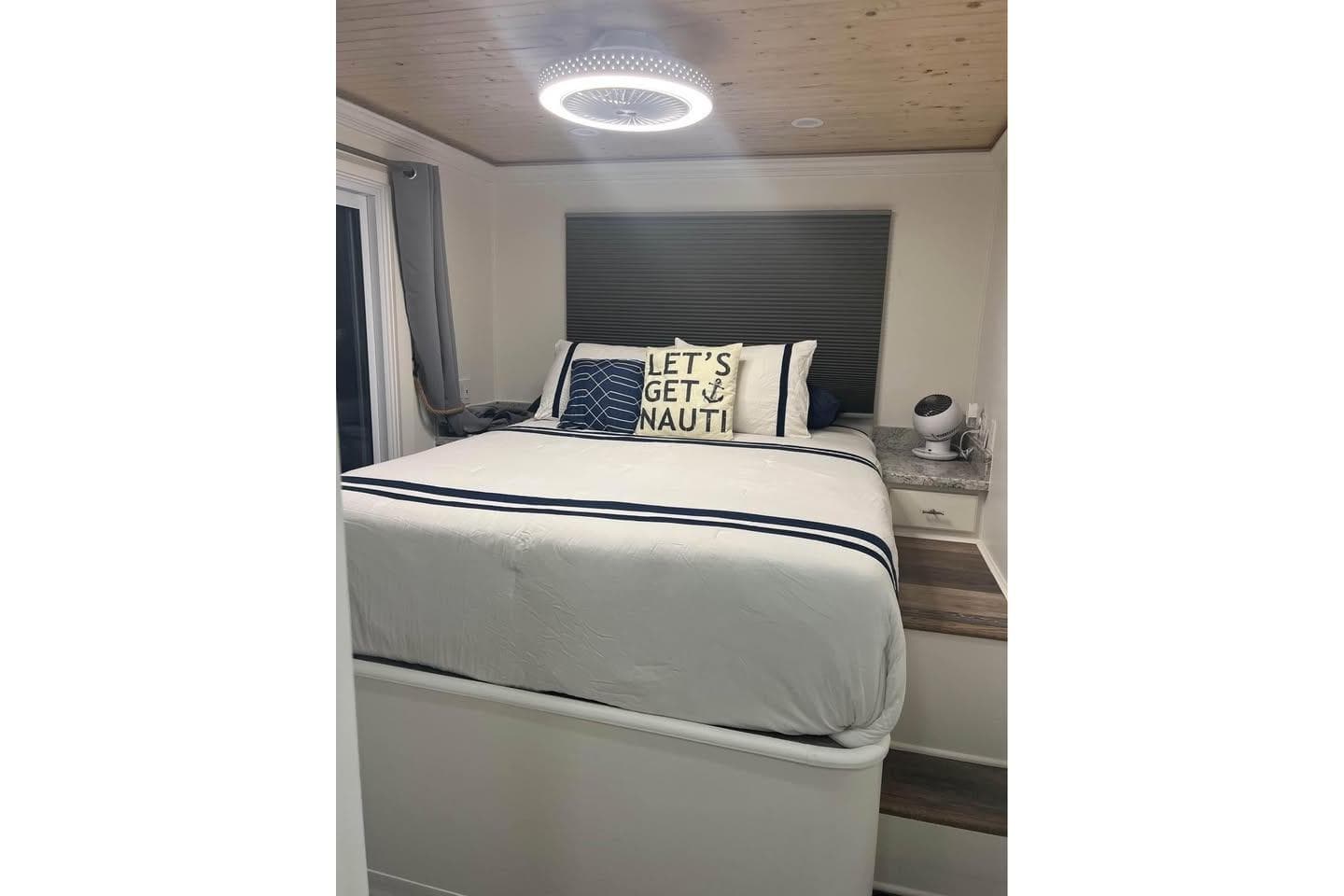 Cozy bedroom in a 1999 Sharpe houseboat with nautical-themed decor and modern lighting.