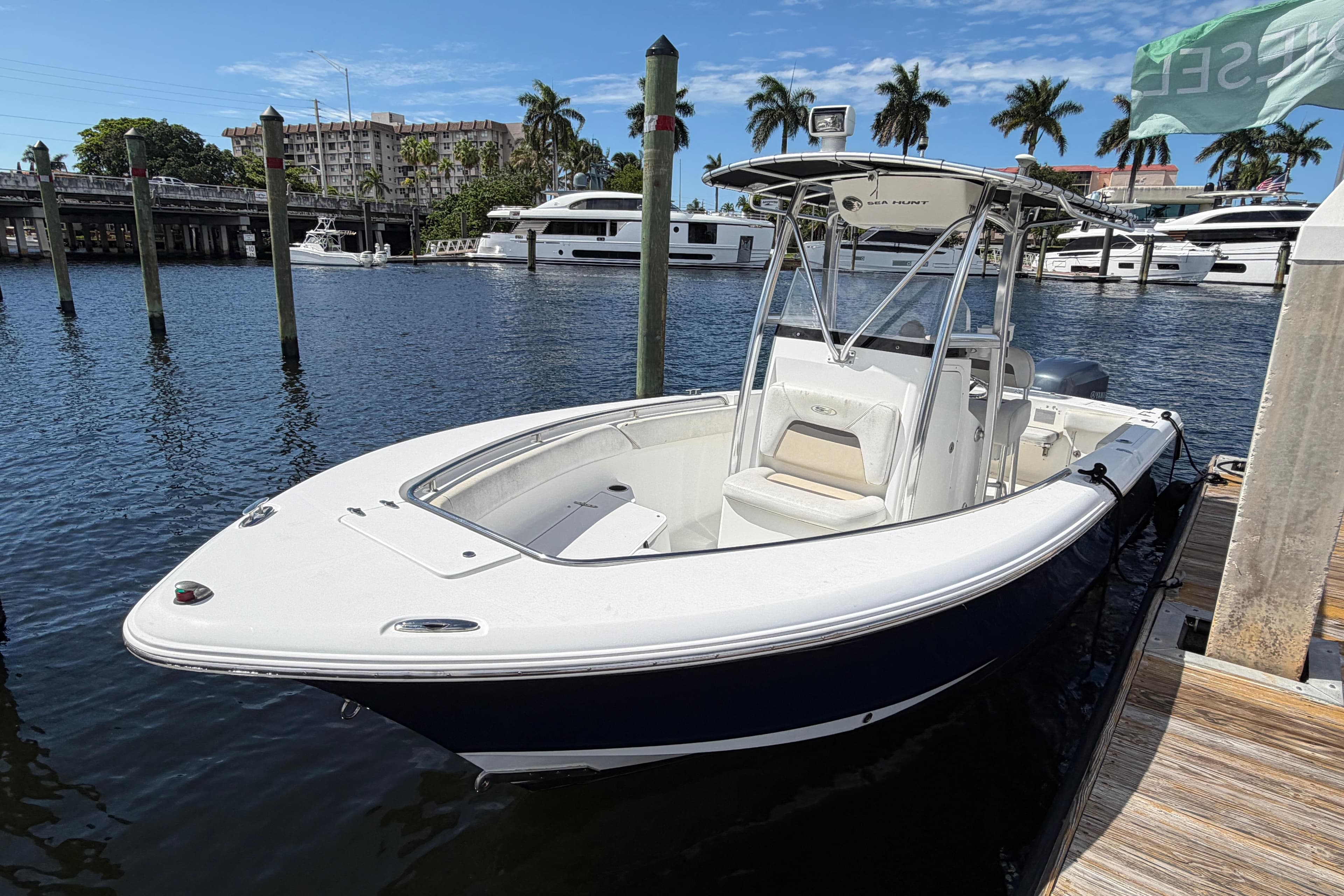 2010 Sea Hunt Gamefish 24 boat docked in marina with yachts and palm trees.