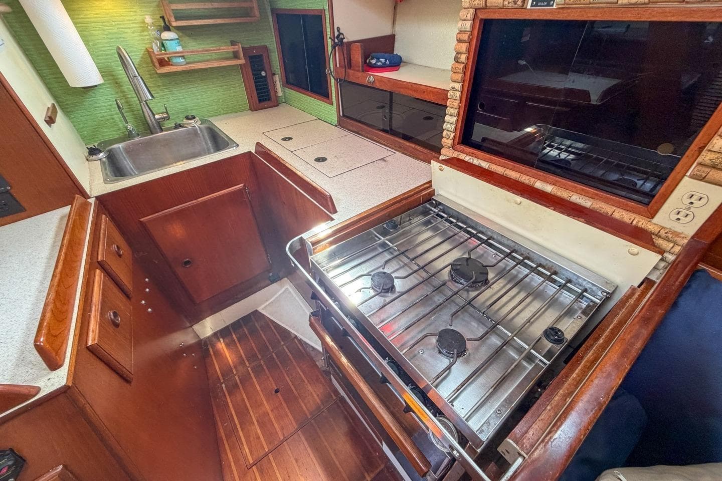1984 Pearson 385 yacht kitchen with stove, sink, and wooden cabinetry.