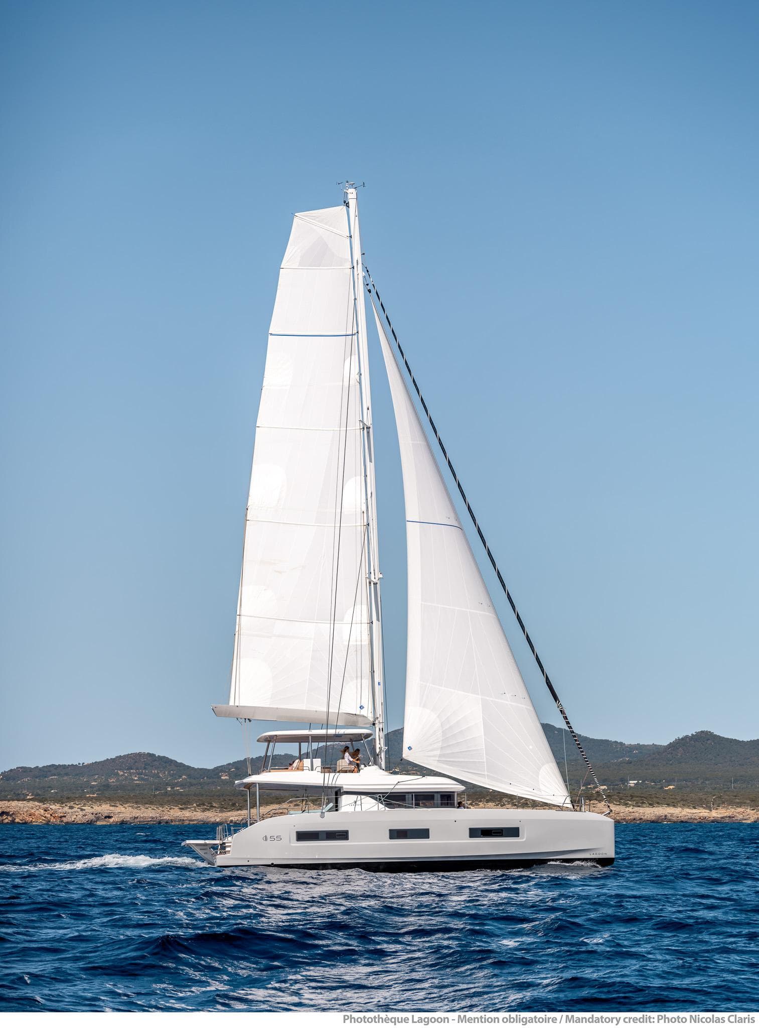 2025 Lagoon 55 sailing catamaran on open sea with clear blue sky.