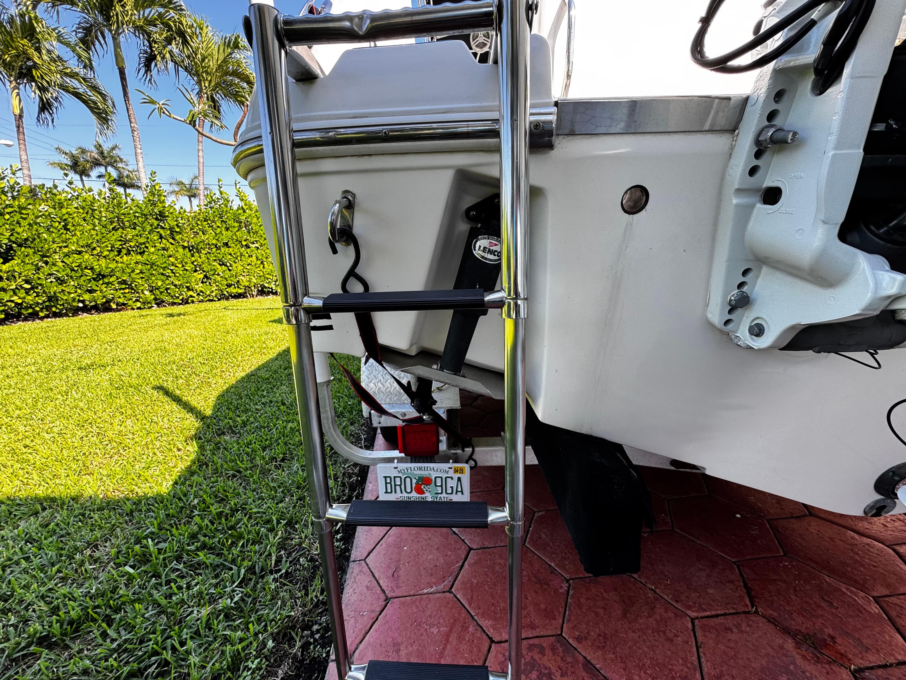 2004 Robalo R 260 boat ladder on red brick patio, surrounded by lush greenery.