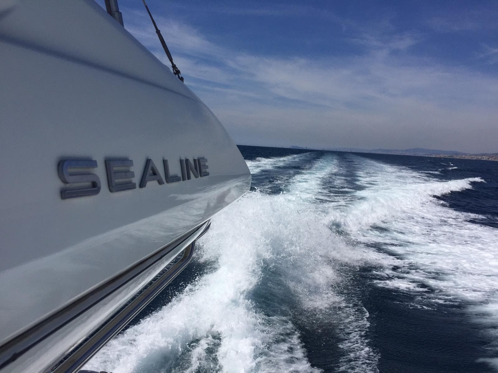 Sealine T60 yacht cruising on open water, leaving a foamy wake behind.