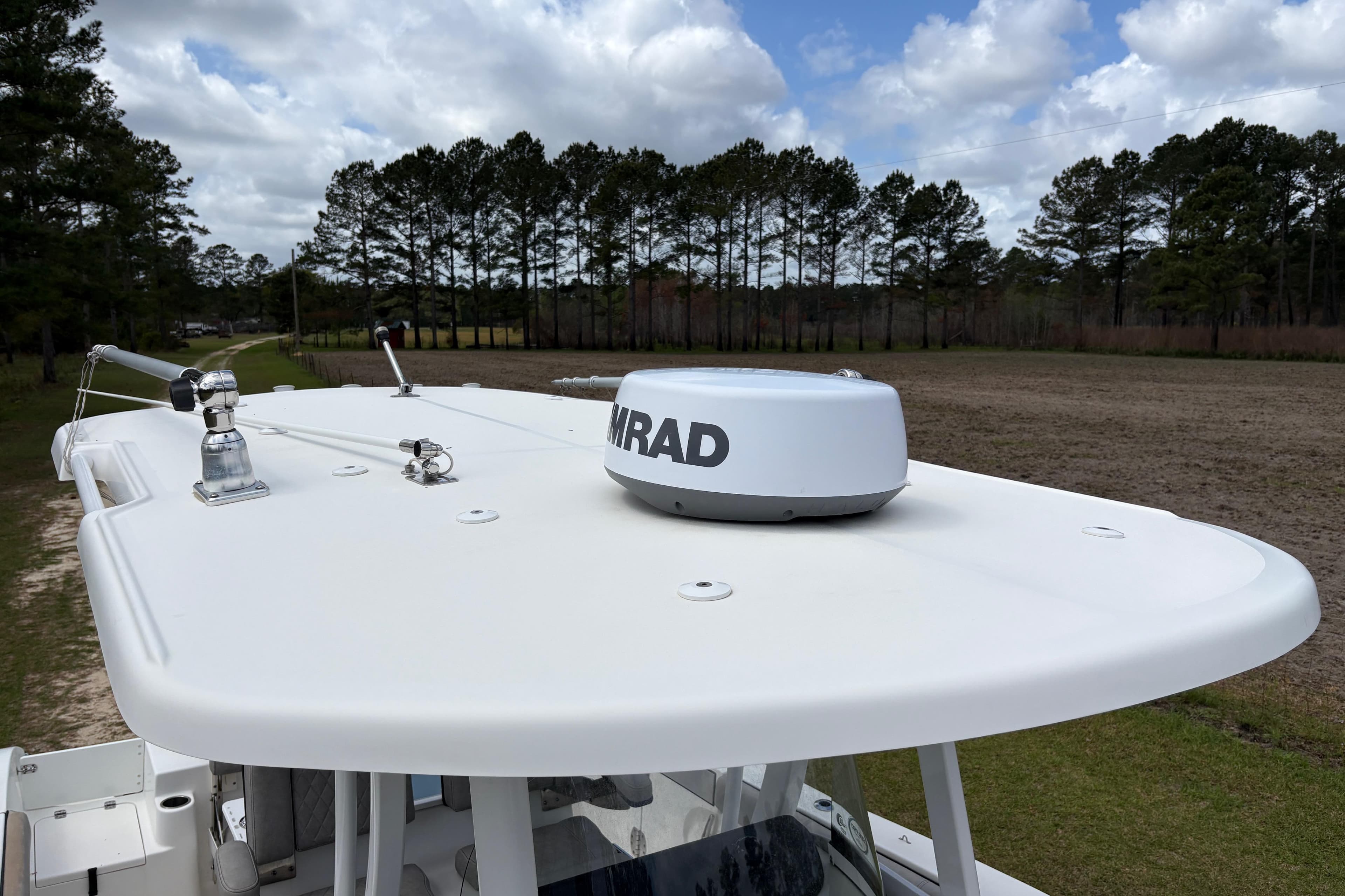 2021 Sea Pro 259 DLX boat with radar on top, surrounded by trees and cloudy sky.