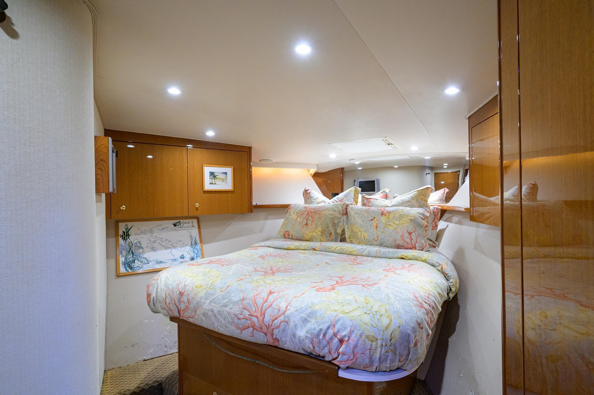Luxurious bedroom interior of 2004 Viking 48 Convertible yacht with elegant bedding and wood cabinetry.