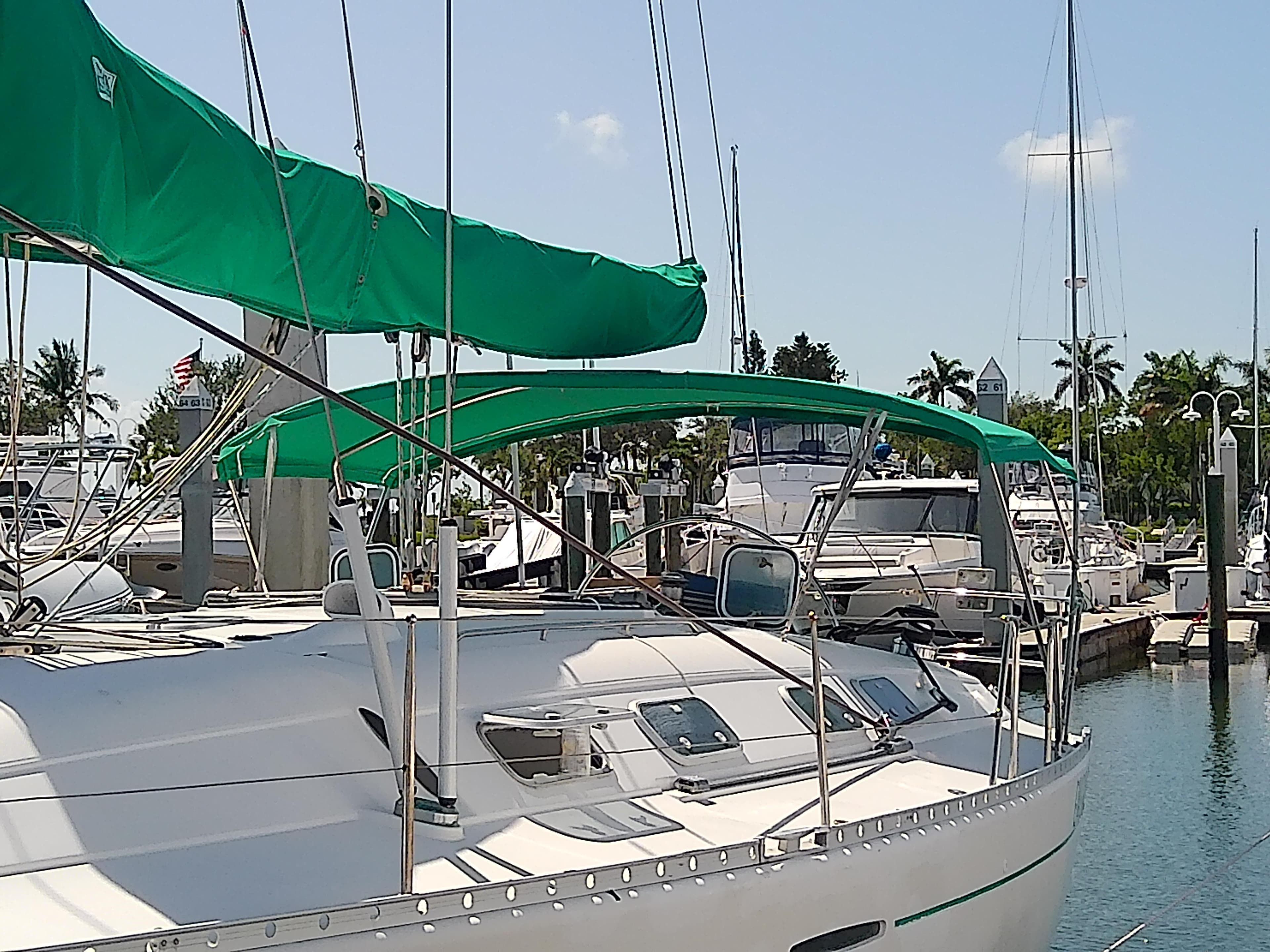 Sailboat Beneteau First 42s7, 1995 model, docked in a marina with green covers.