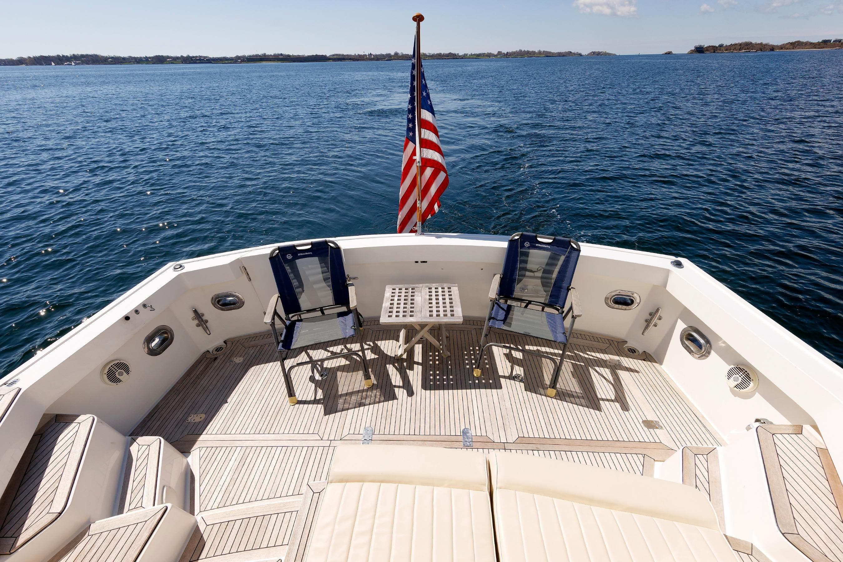 Luxury Eastbay 49 yacht deck with chairs, table, and American flag, cruising on open water.