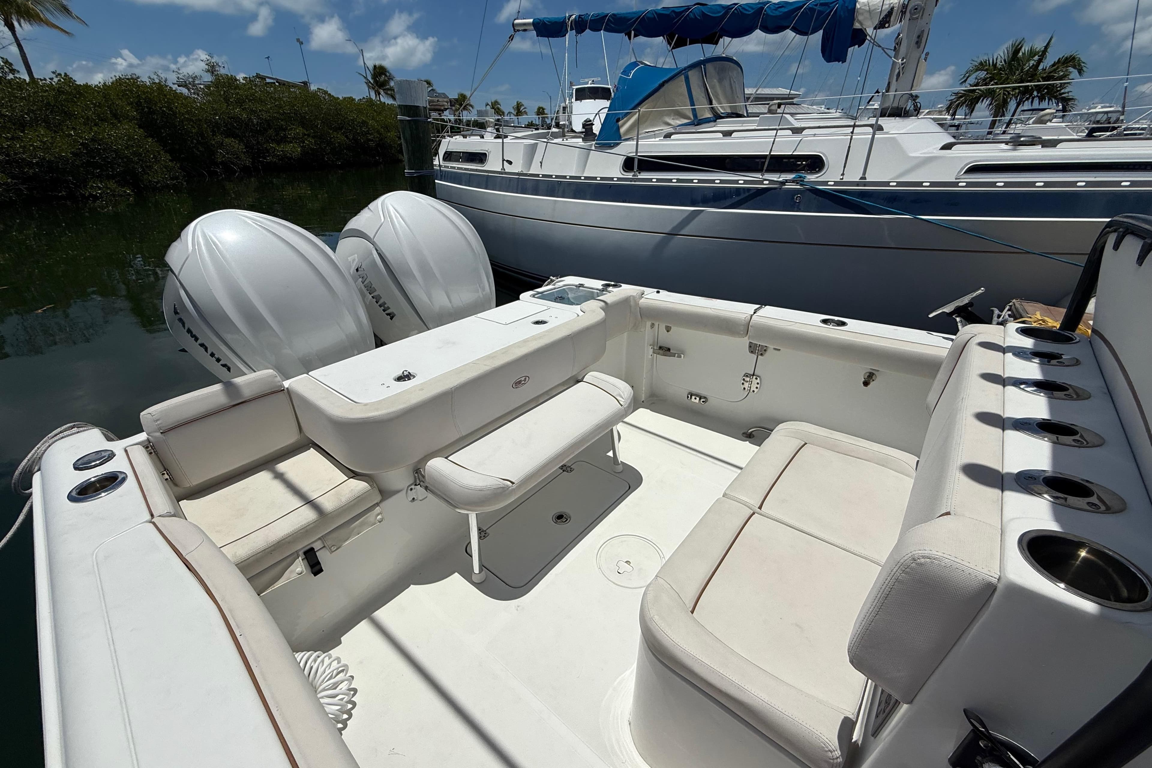 2022 Sea Hunt Gamefish 30 Coffin Box with dual Yamaha engines, docked near sailboat.