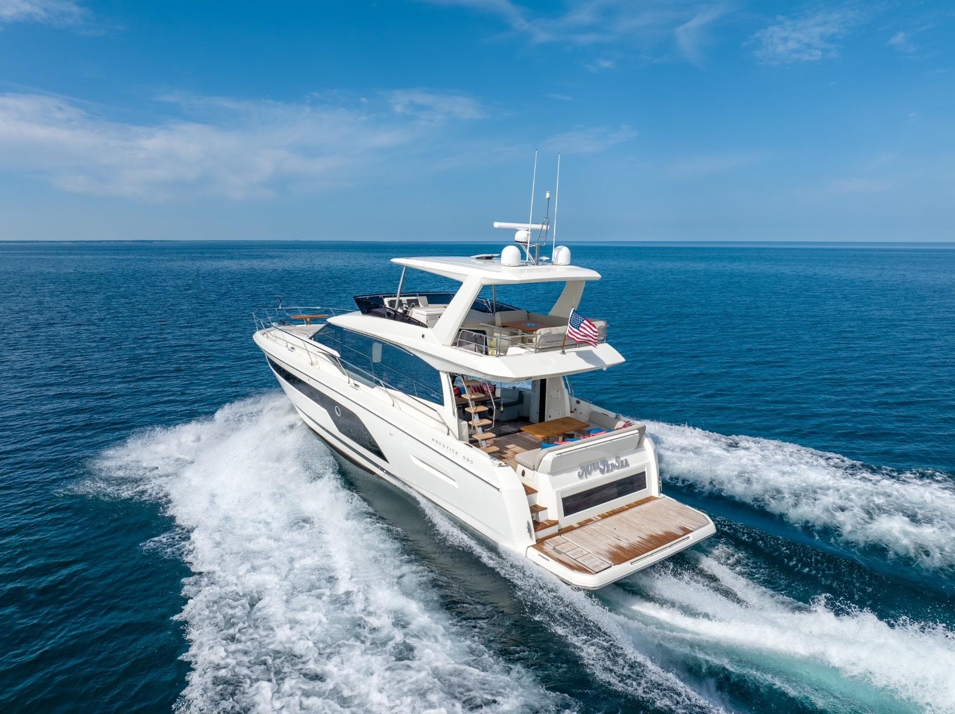 2020 Prestige 590 Flybridge Cruiser sailing on open sea under clear blue sky.