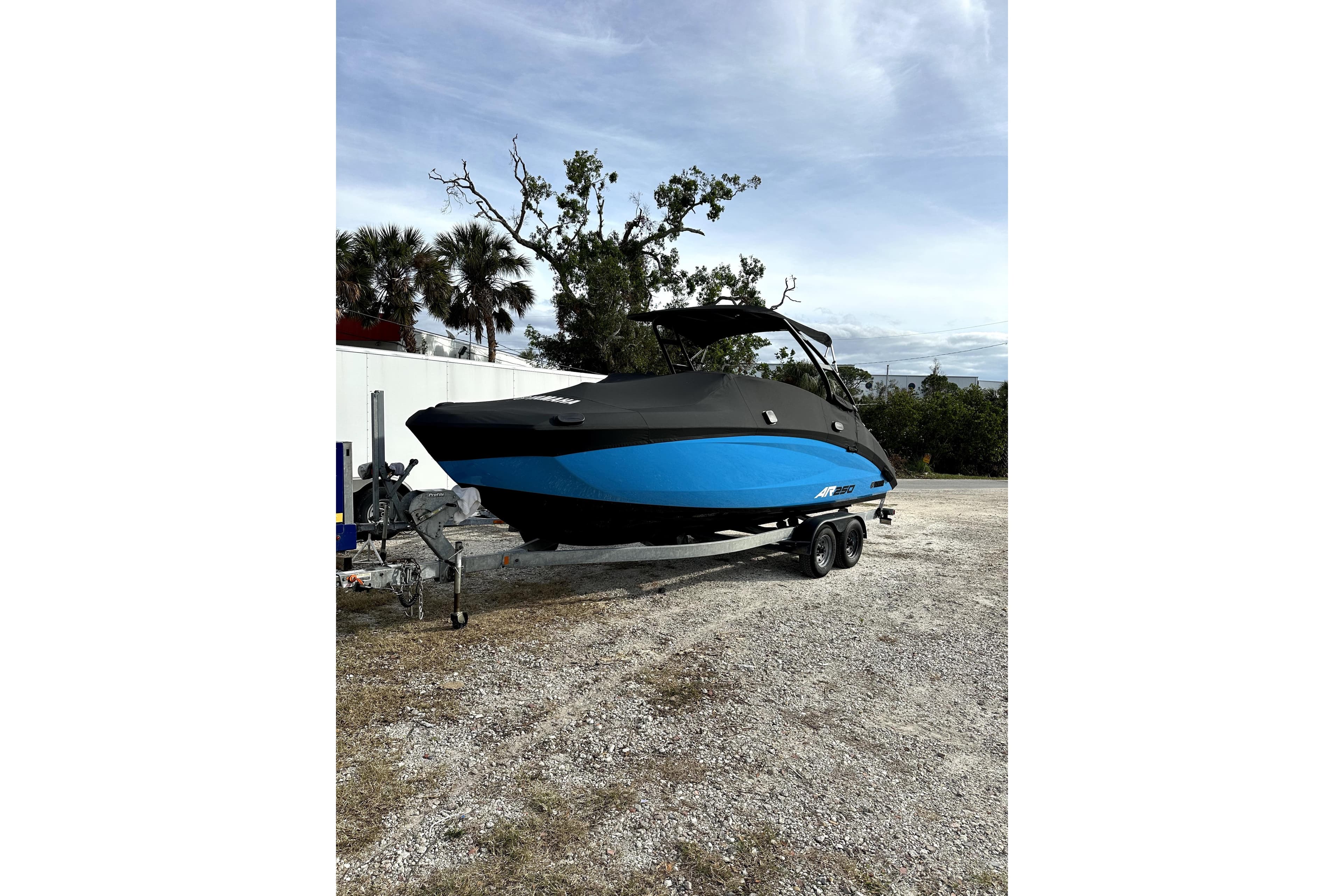 2023 Yamaha Boats AR250 in black and blue on a trailer, parked outdoors.