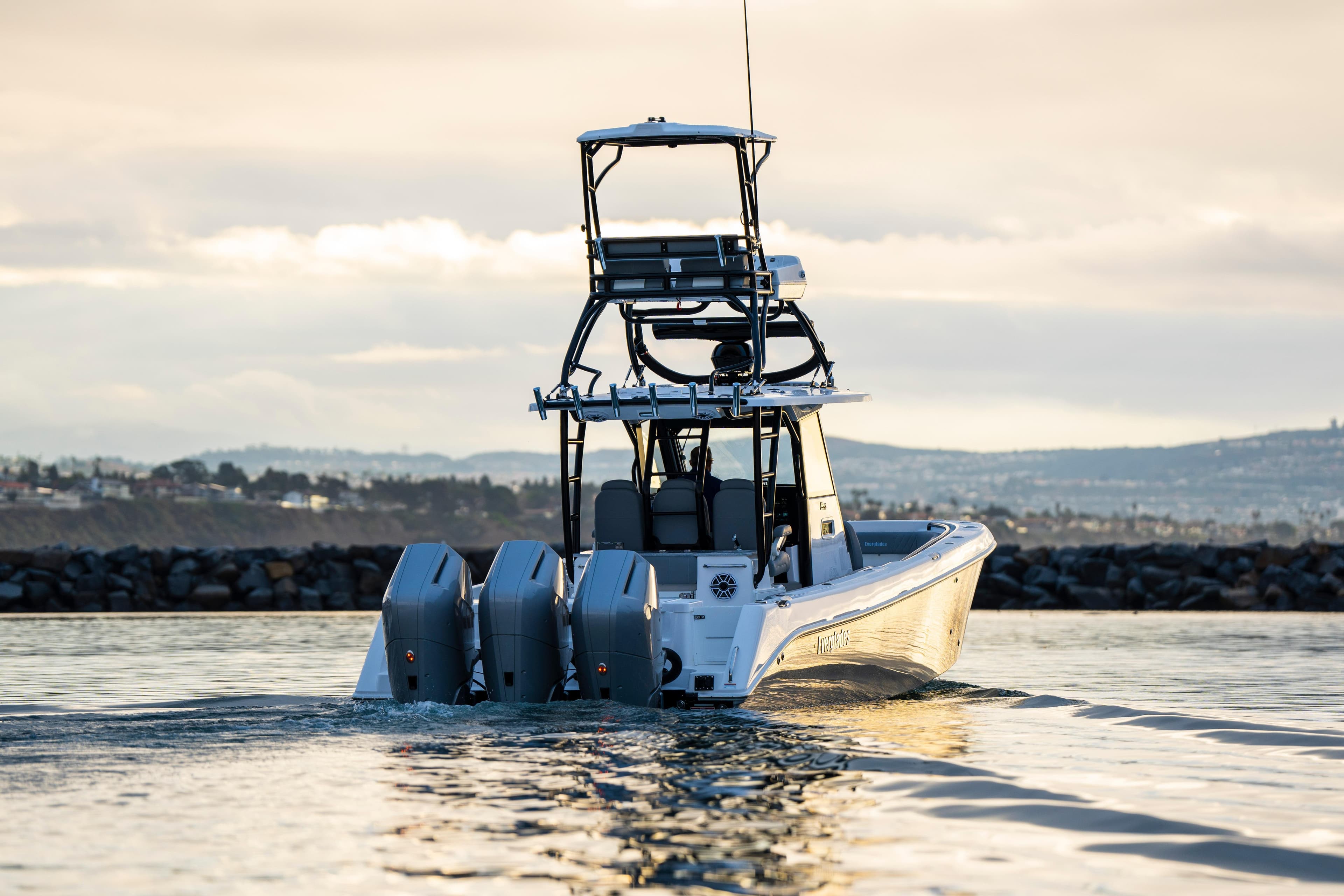 2024 Everglades 365 Center Console boat cruising on calm water at sunset.