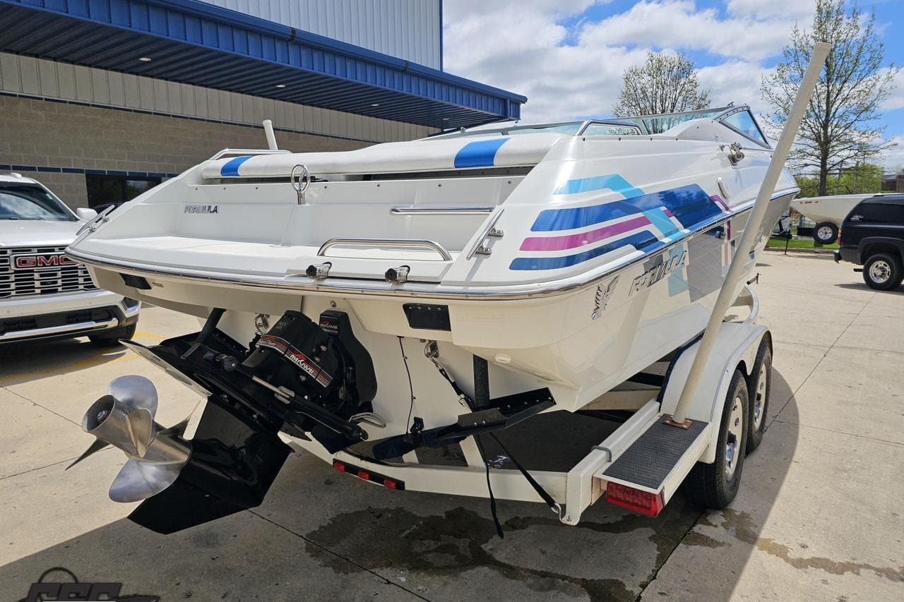 1997 Formula 252 SS boat on trailer, featuring colorful graphics and dual propeller.