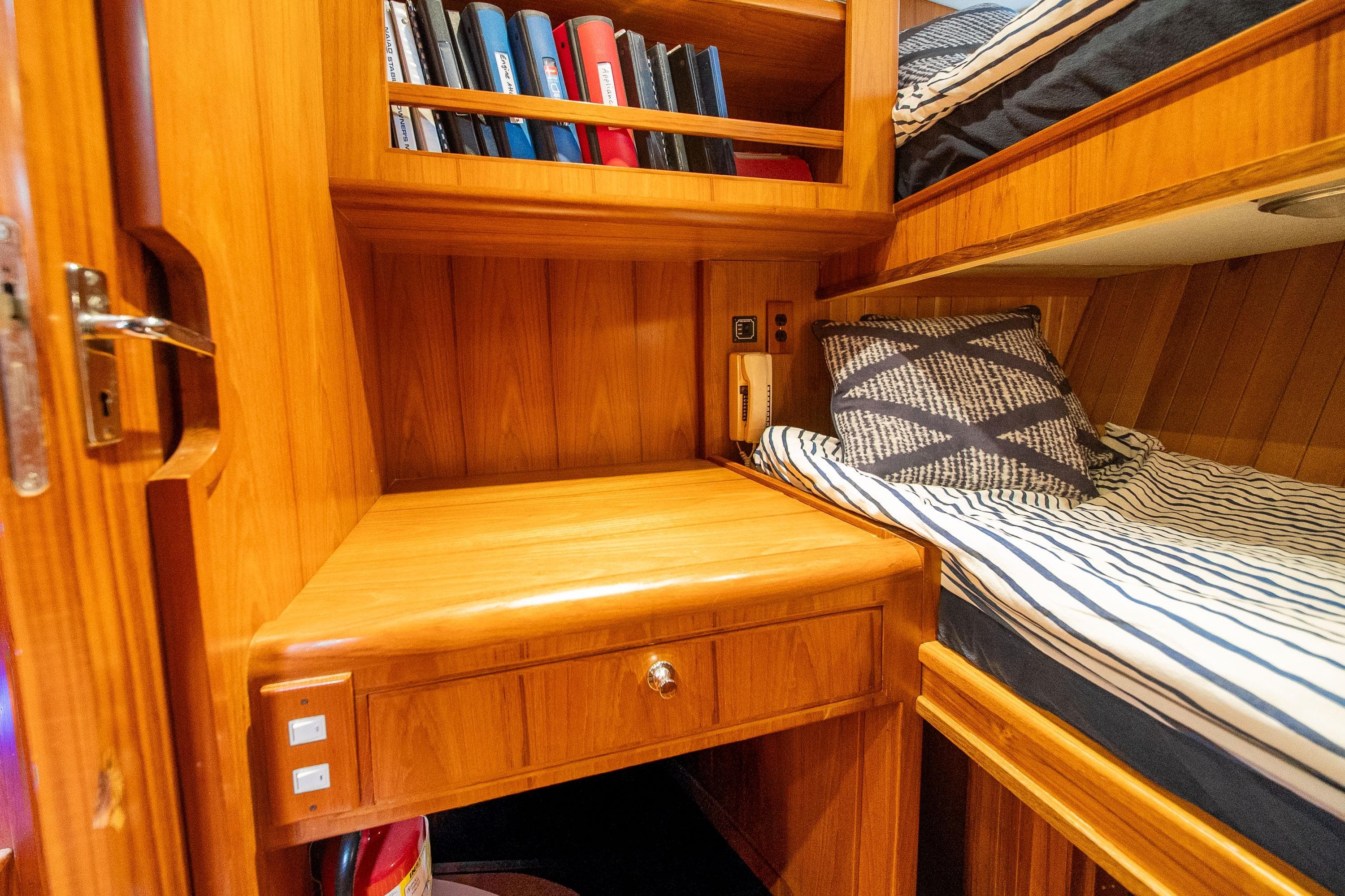 Cozy cabin interior of 2000 Grand Alaskan Pilothouse Trawler with wooden desk and bunk bed.