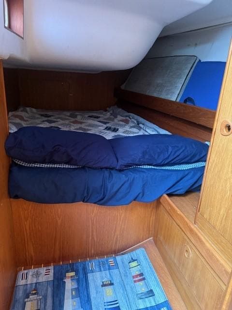 Cozy cabin interior of 2003 Wauquiez Centurion 45s sailboat with wooden finish and bedding.
