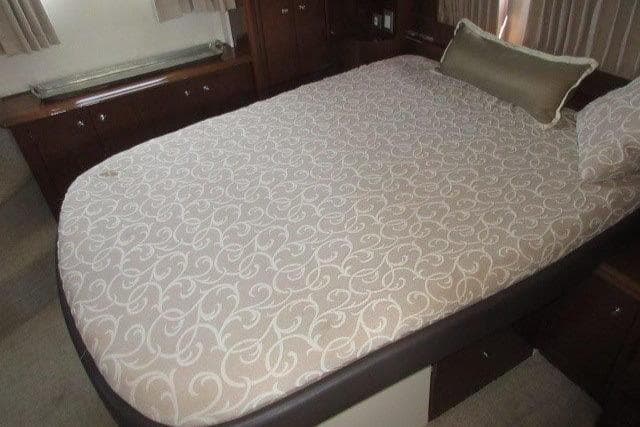 2008 Carver 47 Motor Yacht bedroom with patterned bedspread and wooden cabinetry.