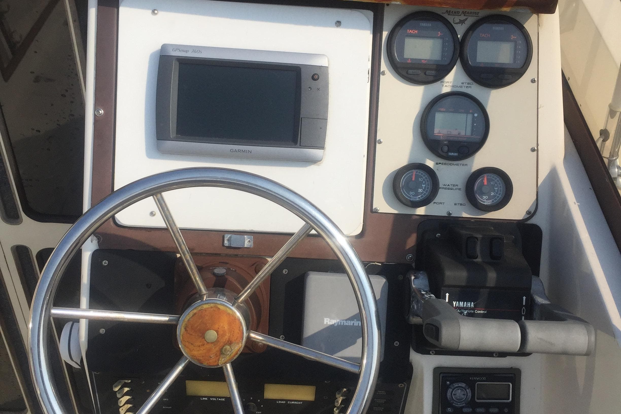 1991 Mako 260 Walk Around boat dashboard with steering wheel and gauges.