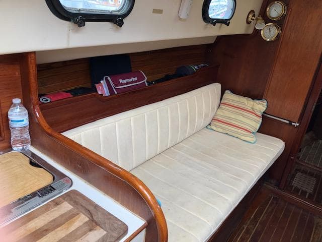 Interior of 1983 Cape Dory 28 sailboat with white cushioned seating and wooden accents.